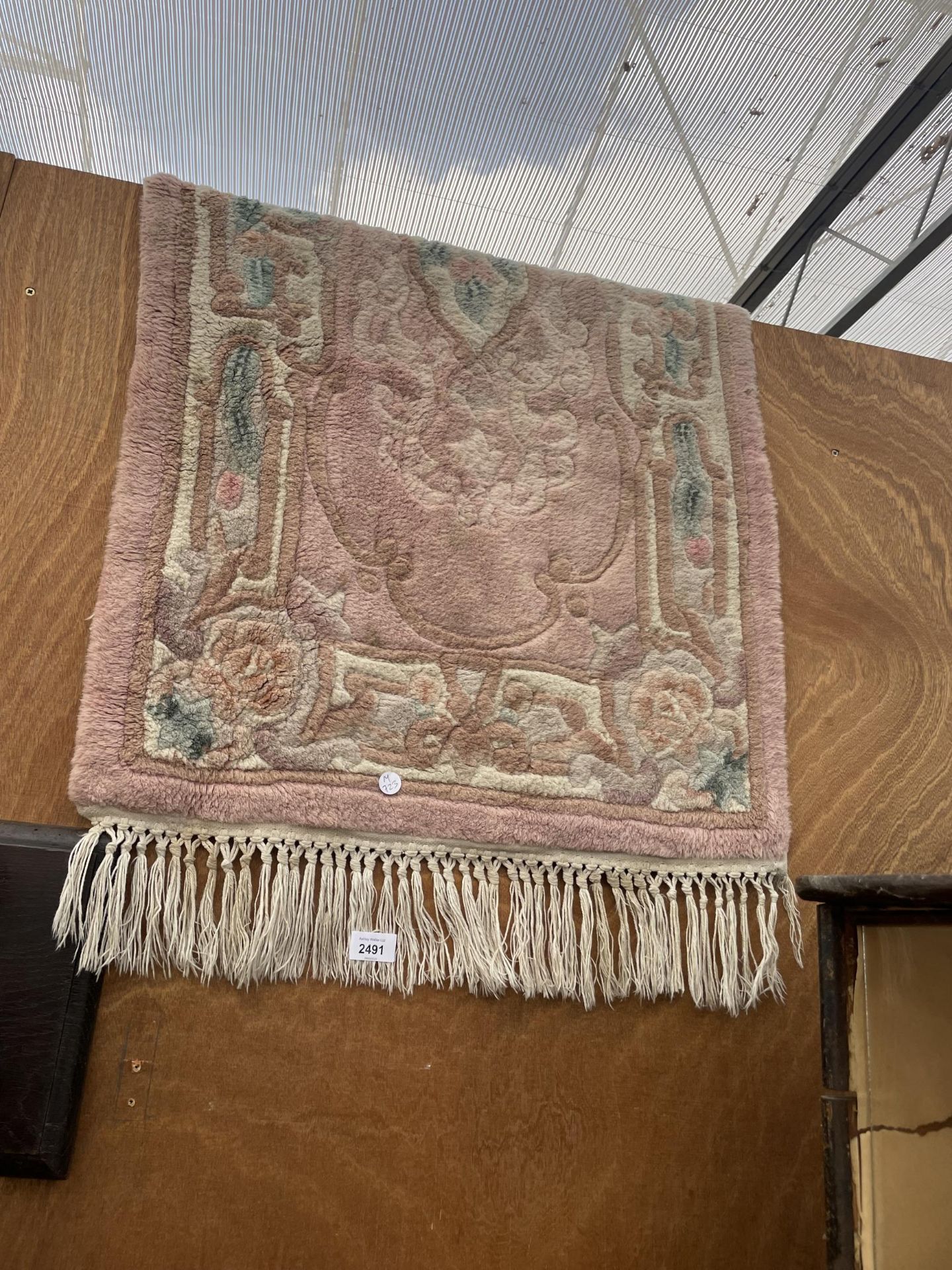 A SMALL PINK PATTERNED FRINGED RUG