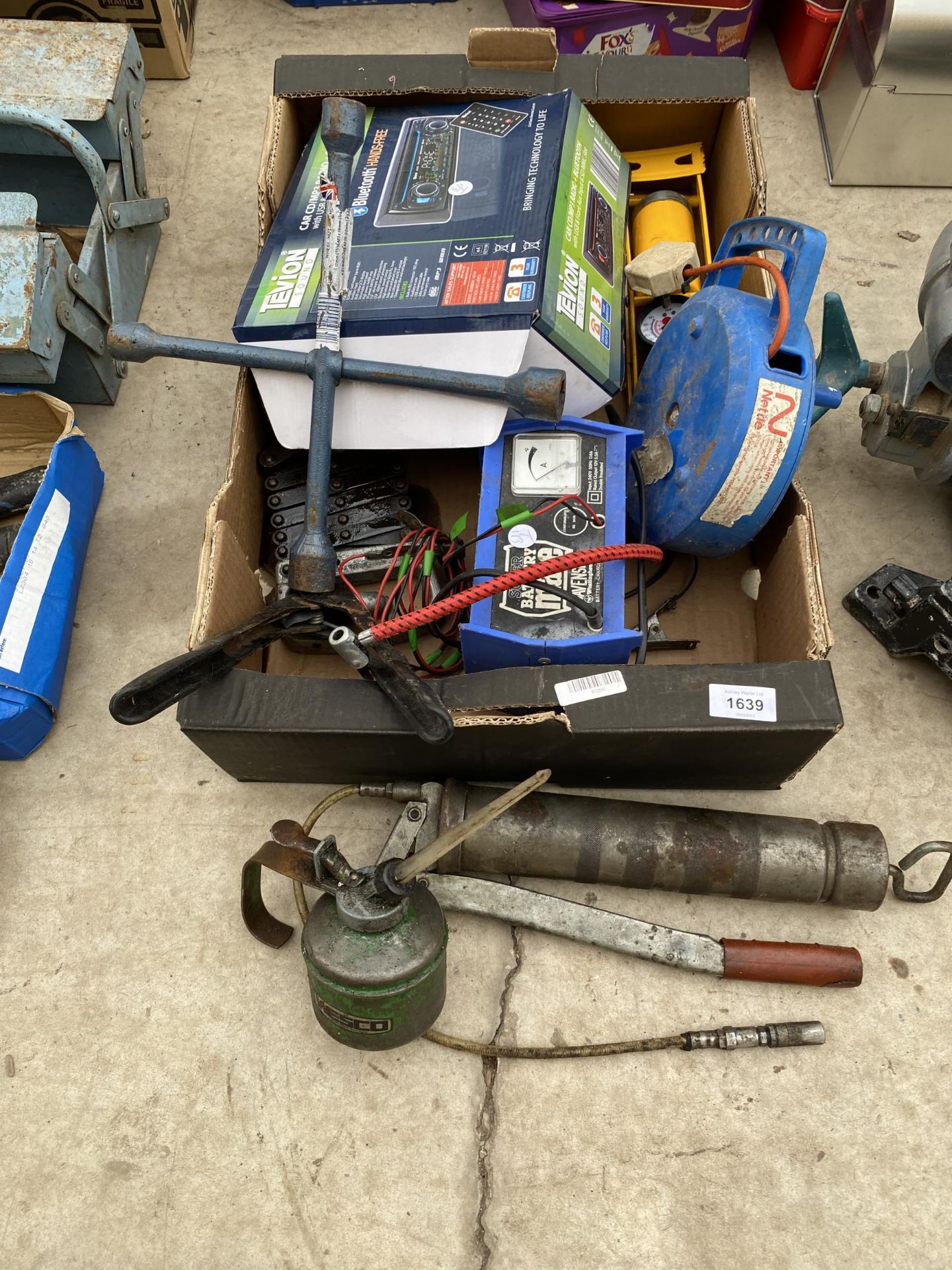 AN ASSORTMENT OF TOOLS TO INCLUDE A GREASE GUN, OIL CAN AND BATTERY CHARGER ETC