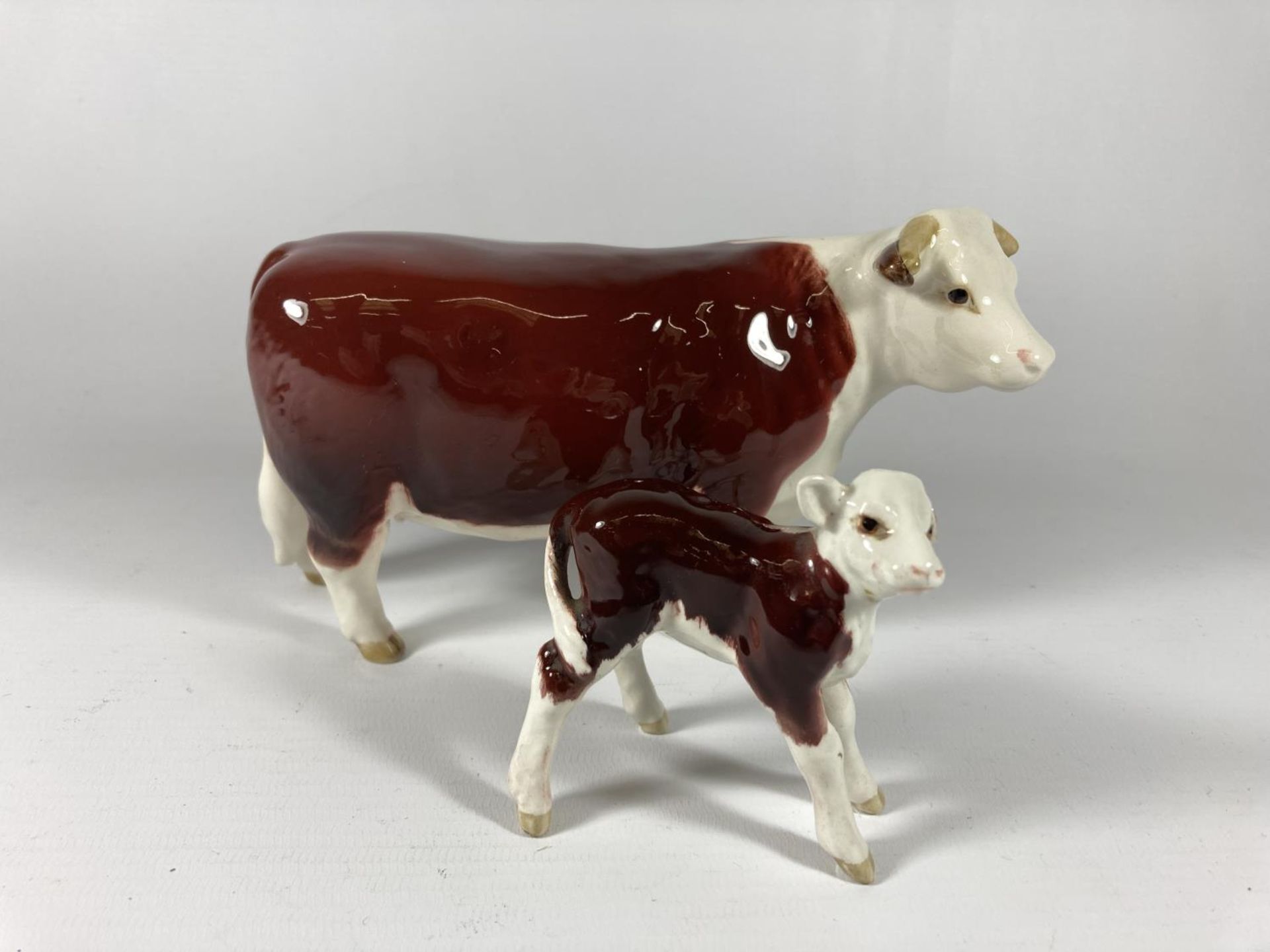 A BESWICK HEREFORD COW AND CALF (CALF EAR A/F)