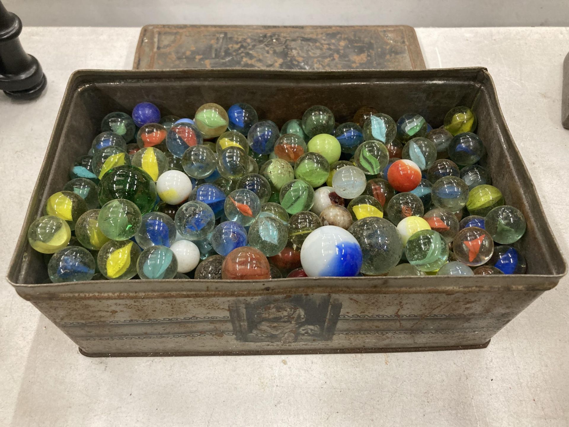 A VINTAGE TIN CONTAINING A QUANTITY OF MARBLES