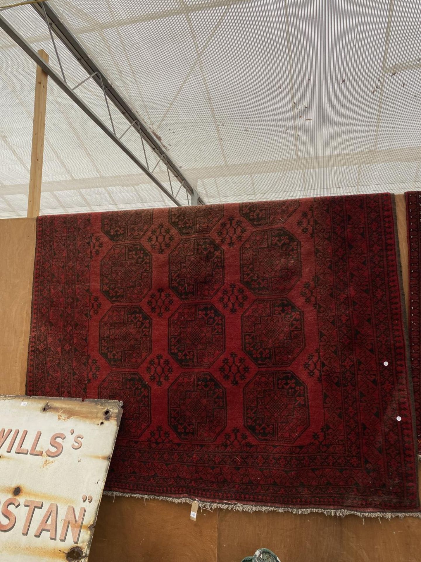 A RED PATTERNED FRINGED RUG (280CM x 209CM)