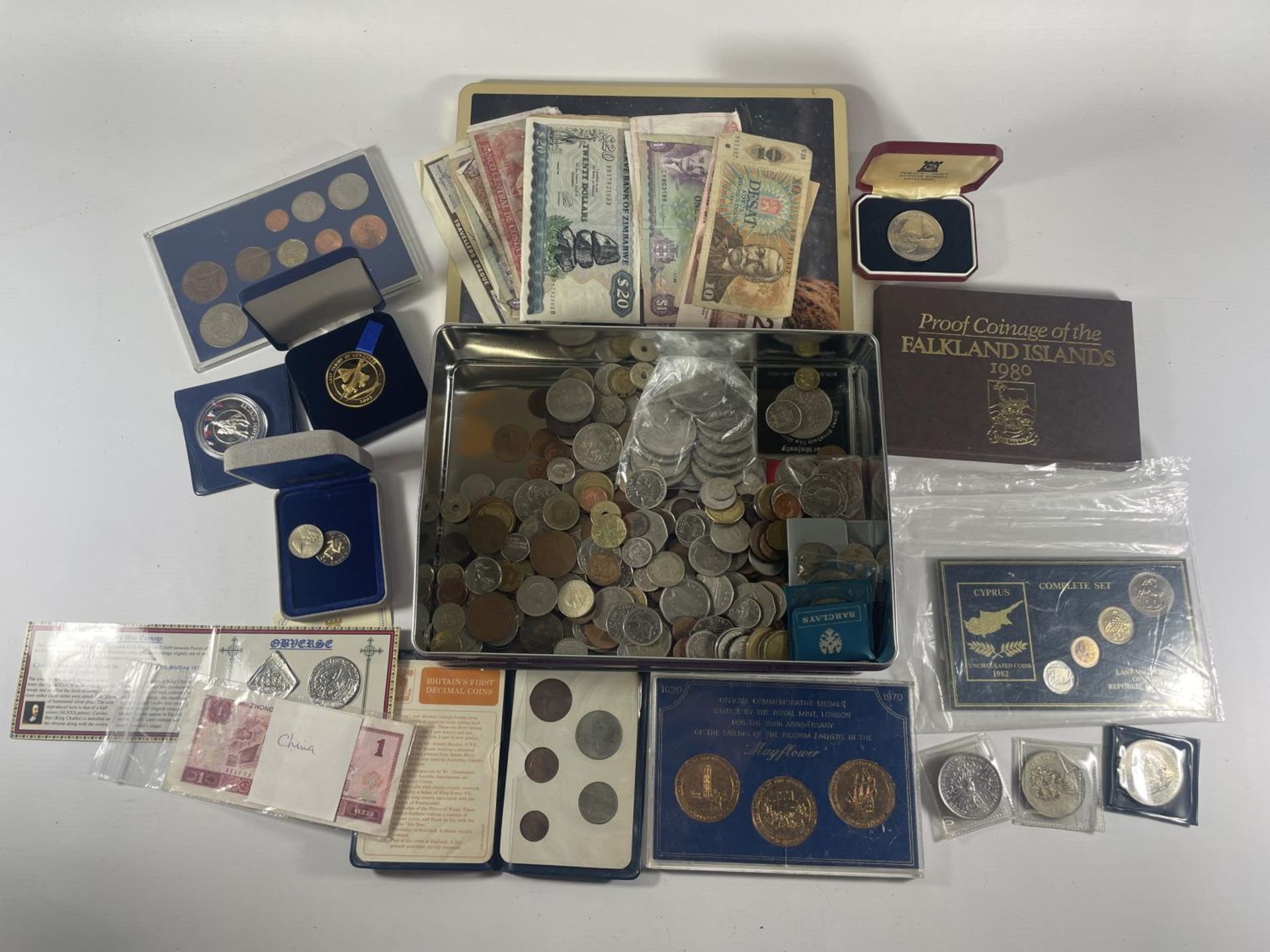 TIN CONTAINING AN ASSORTMENT OF WORLD COINS AND BANKNOTES , TO INCLUDE CHINA , FALKLANDS , IOM