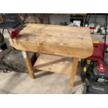 A WOODEN WORK BENCH WITH A SMALL DRAPER BENCH VICE