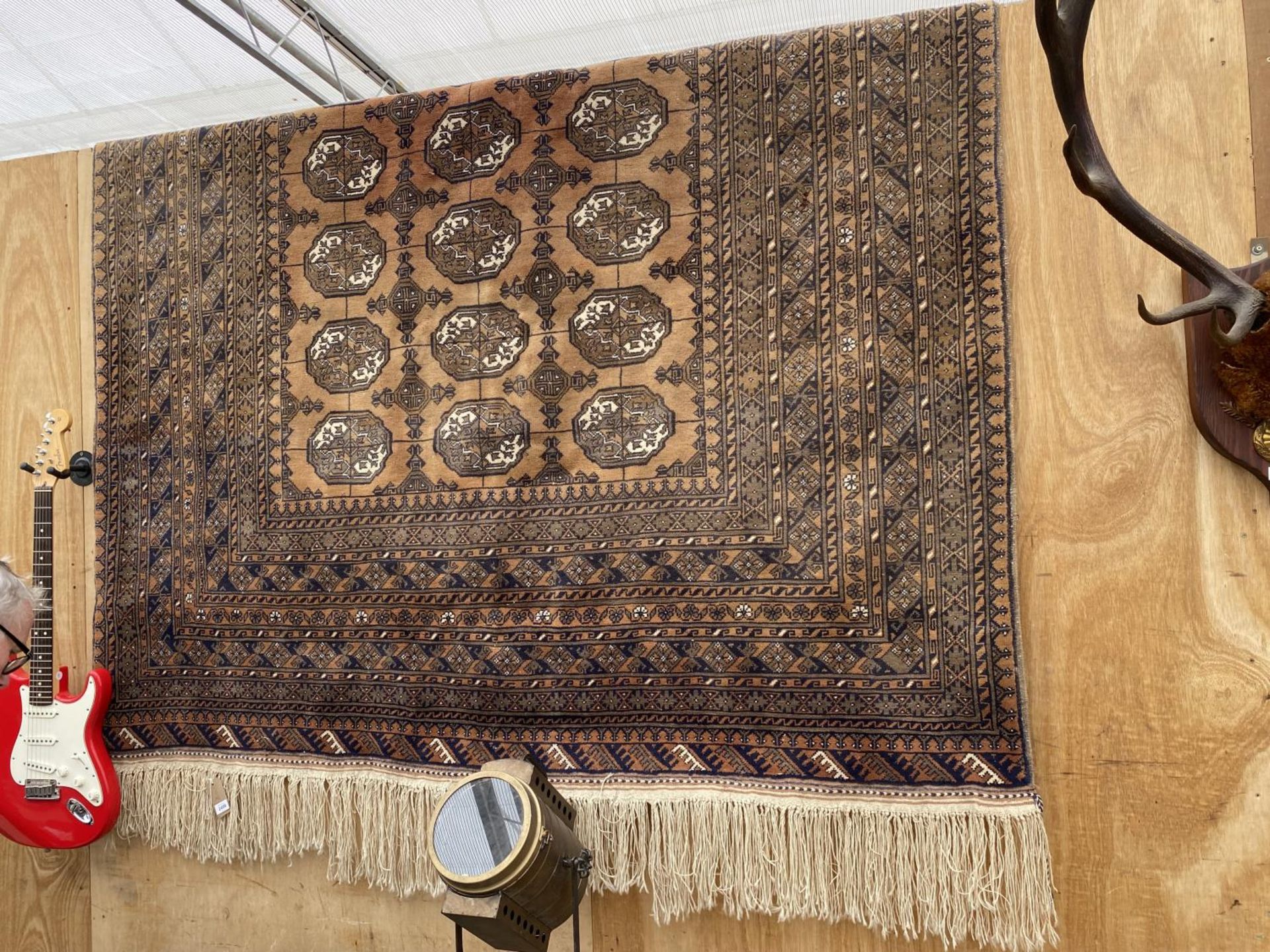 A LARGE ORANGE PATTERNED FRINGED RUG