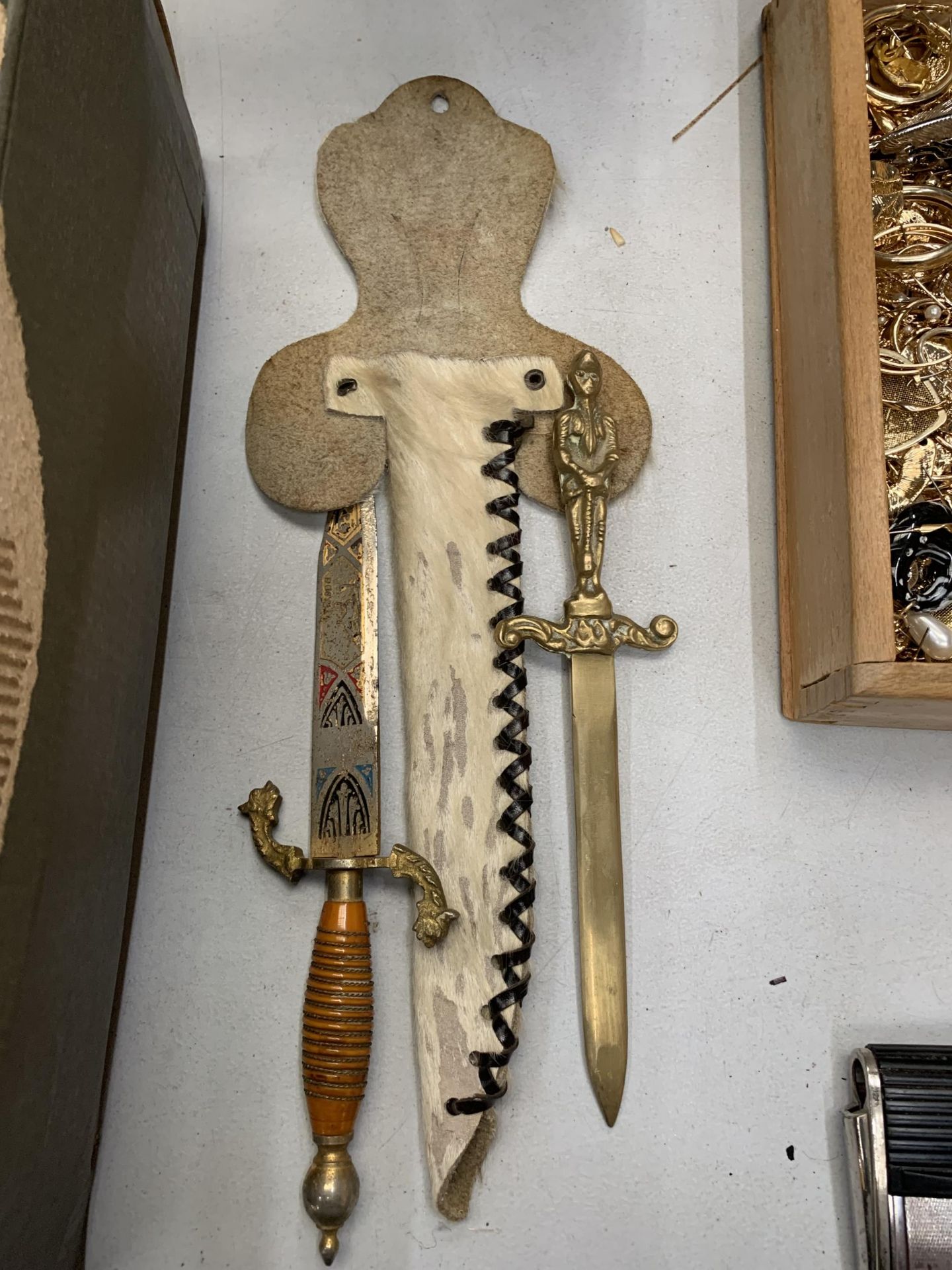 AN ORNATE KNIFE IN AN ANIMAL SKIN SHEATH AND A BRASS LETTER OPENER