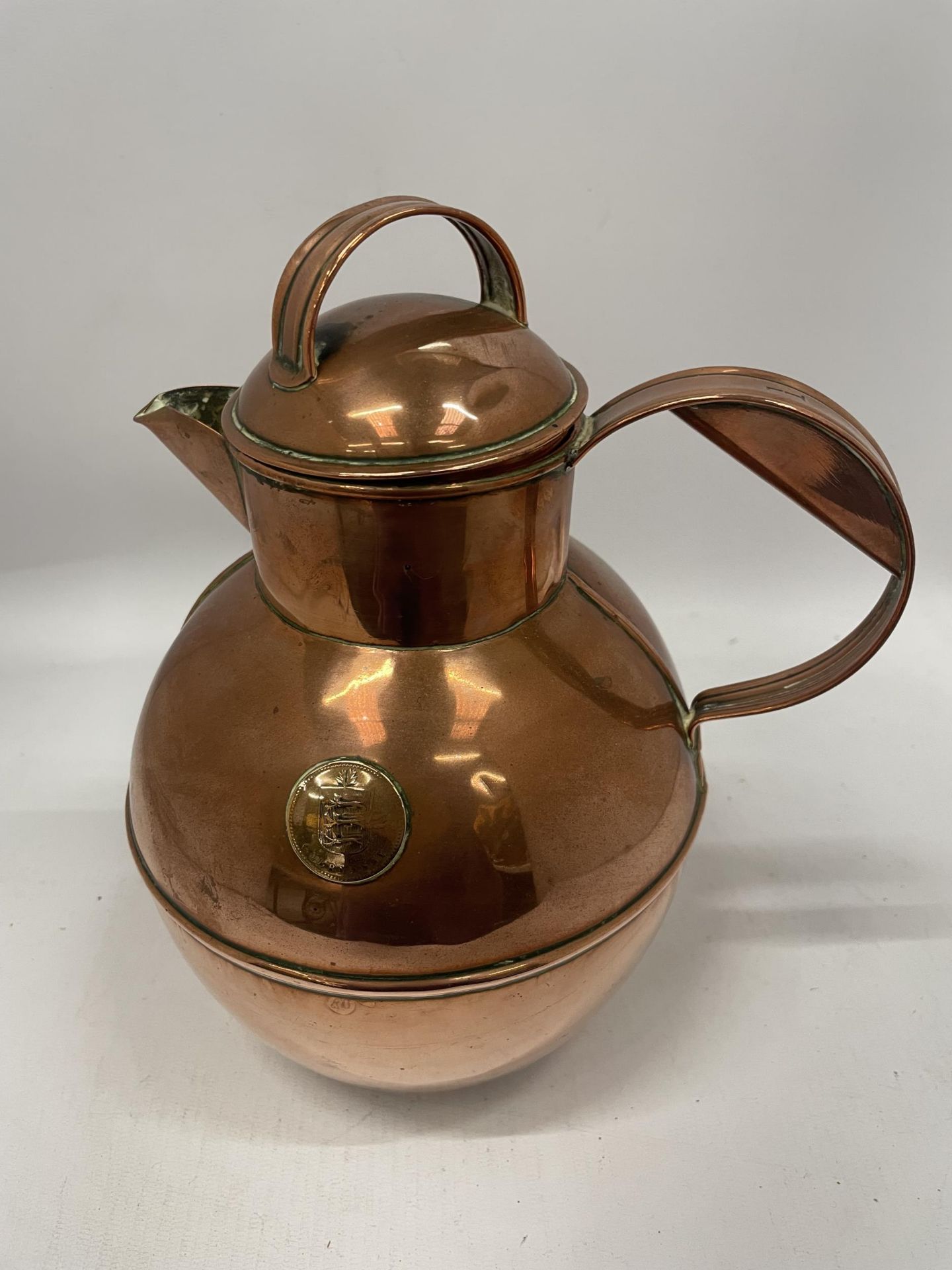 A VINTAGE COPPER KETTLE / WATER JUG WITH INSET GUERNSEY COIN DESIGN