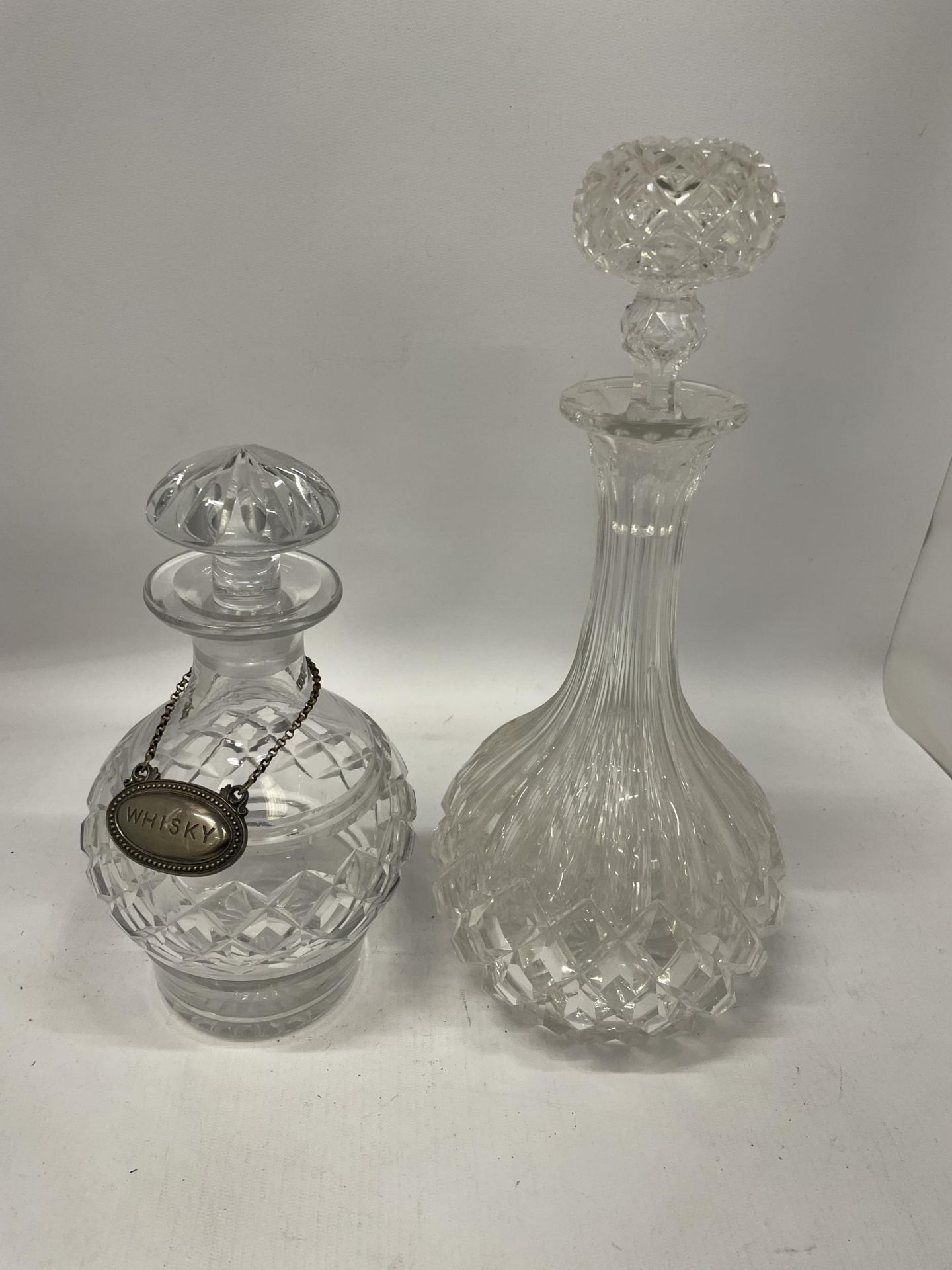 TWO CUT GLASS DECANTERS TOGETHER WITH A VINTAGE SILVER PLATED WHISKY DECANTER LABEL