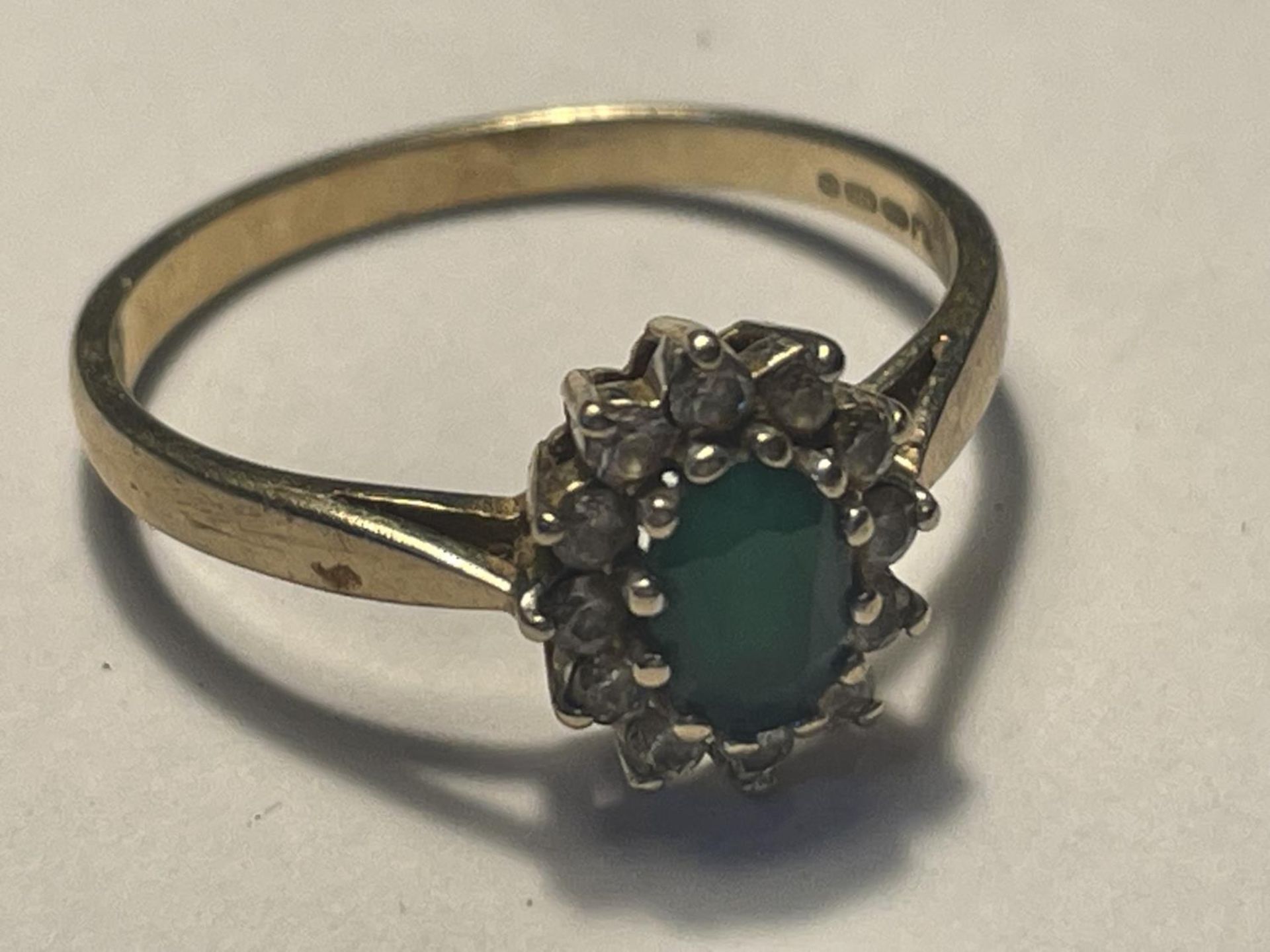 A 9 CARAT GOLD RING WITH CENTRE GREENSTONE SURROUNDED BY CUBIC ZIRCONIAS SIZE P