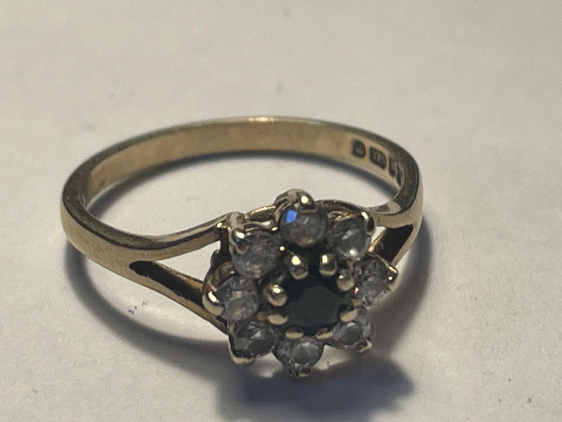 A 9 CARAT GOLD RING WITH A CENTRE SAPPHIRE SURROUNDED BY CUBIC ZIRCONIAS SIZE K/L
