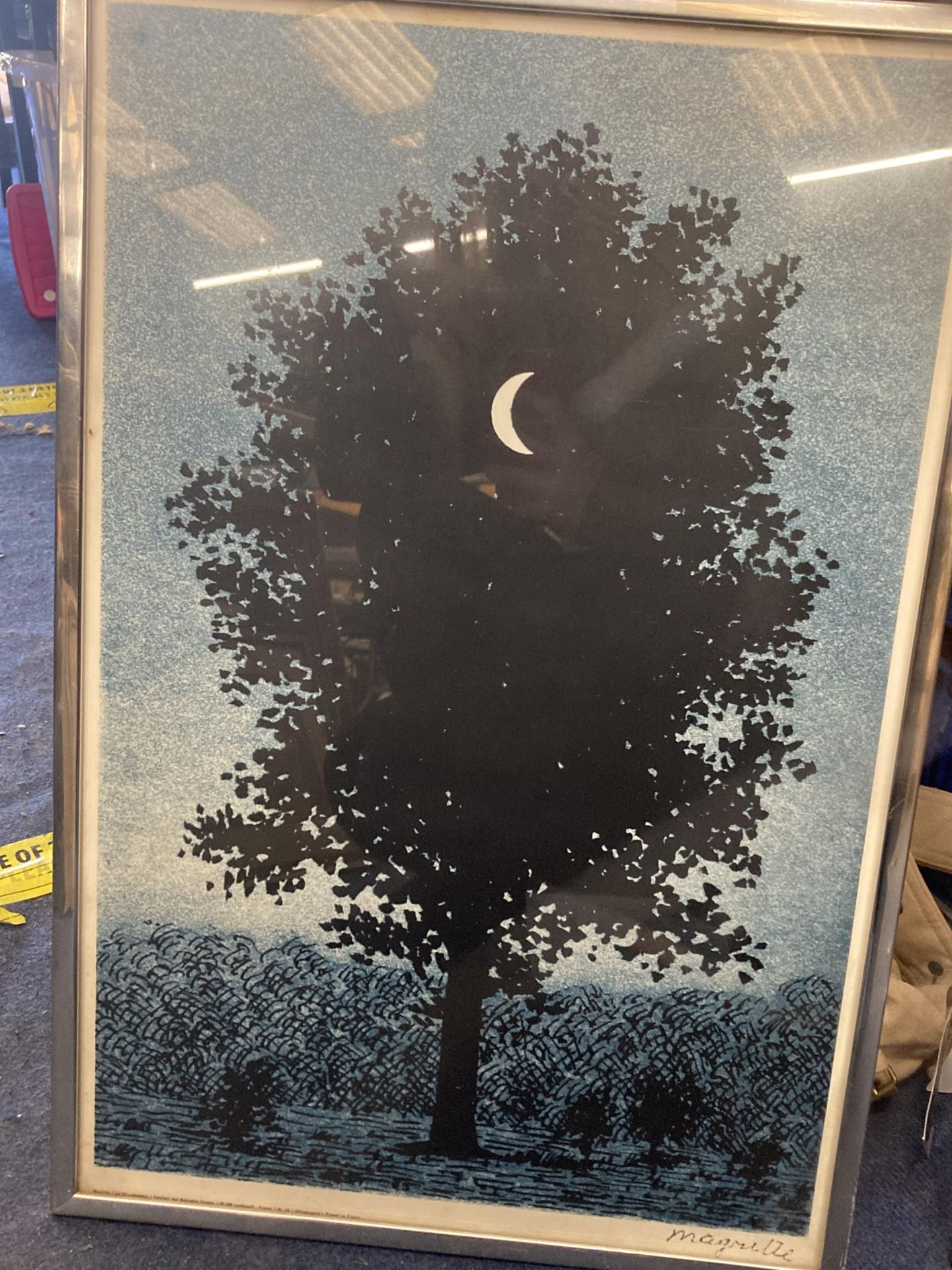 A FRAMED MAGRITTE PRINT OF A SUPERIMPOSED CRESCENT MOON IN FRONT OF A TREE, TITLED LE SEIZE