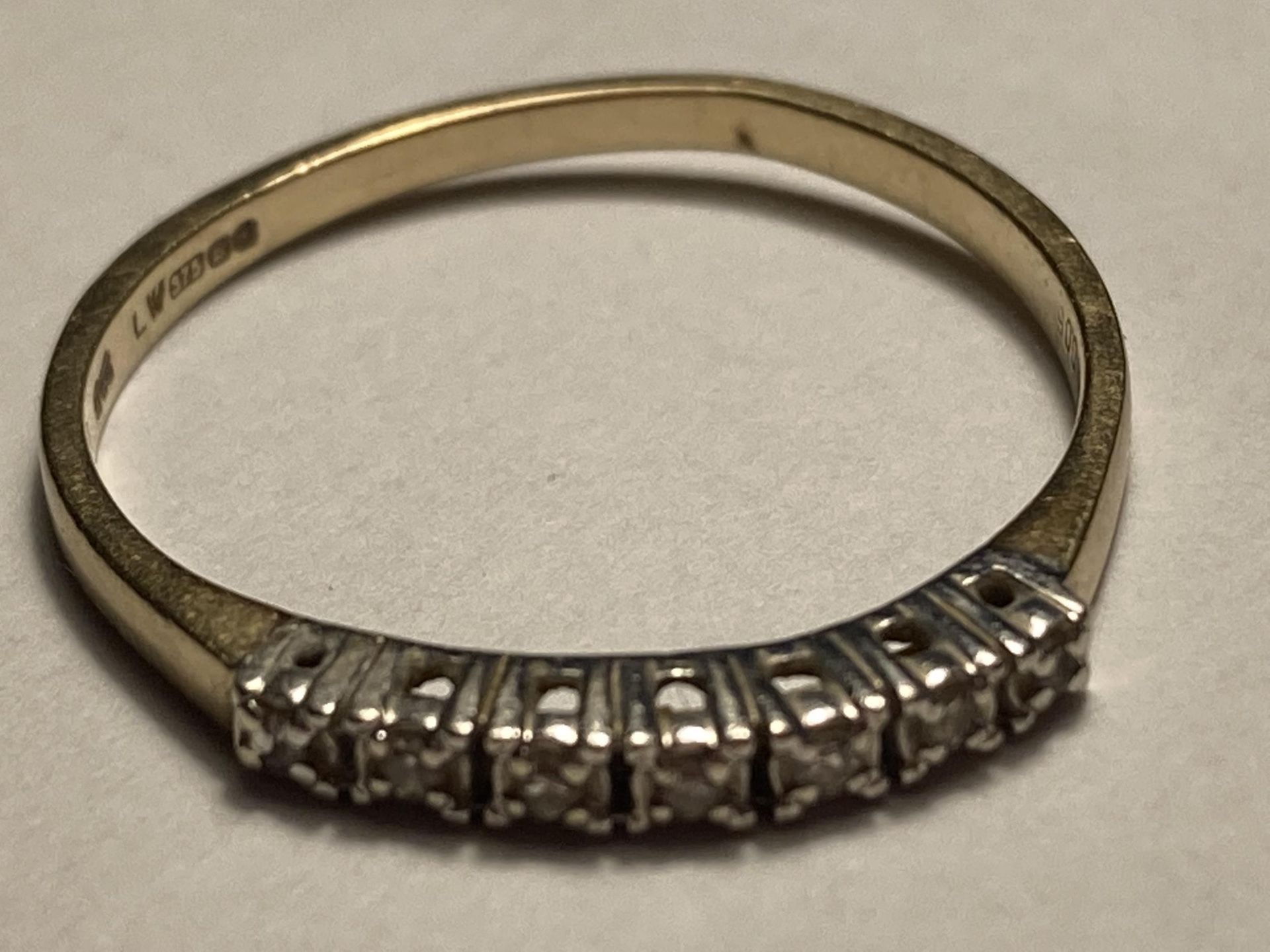 A 9 CARAT GOLD RING WITH SEVEN IN LINE DIAMONDS SIZE O/P