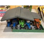 A WOODEN TRACTOR GARAGE CONTAINING A QUANTITY OF TRACTORS AND TRAILERS