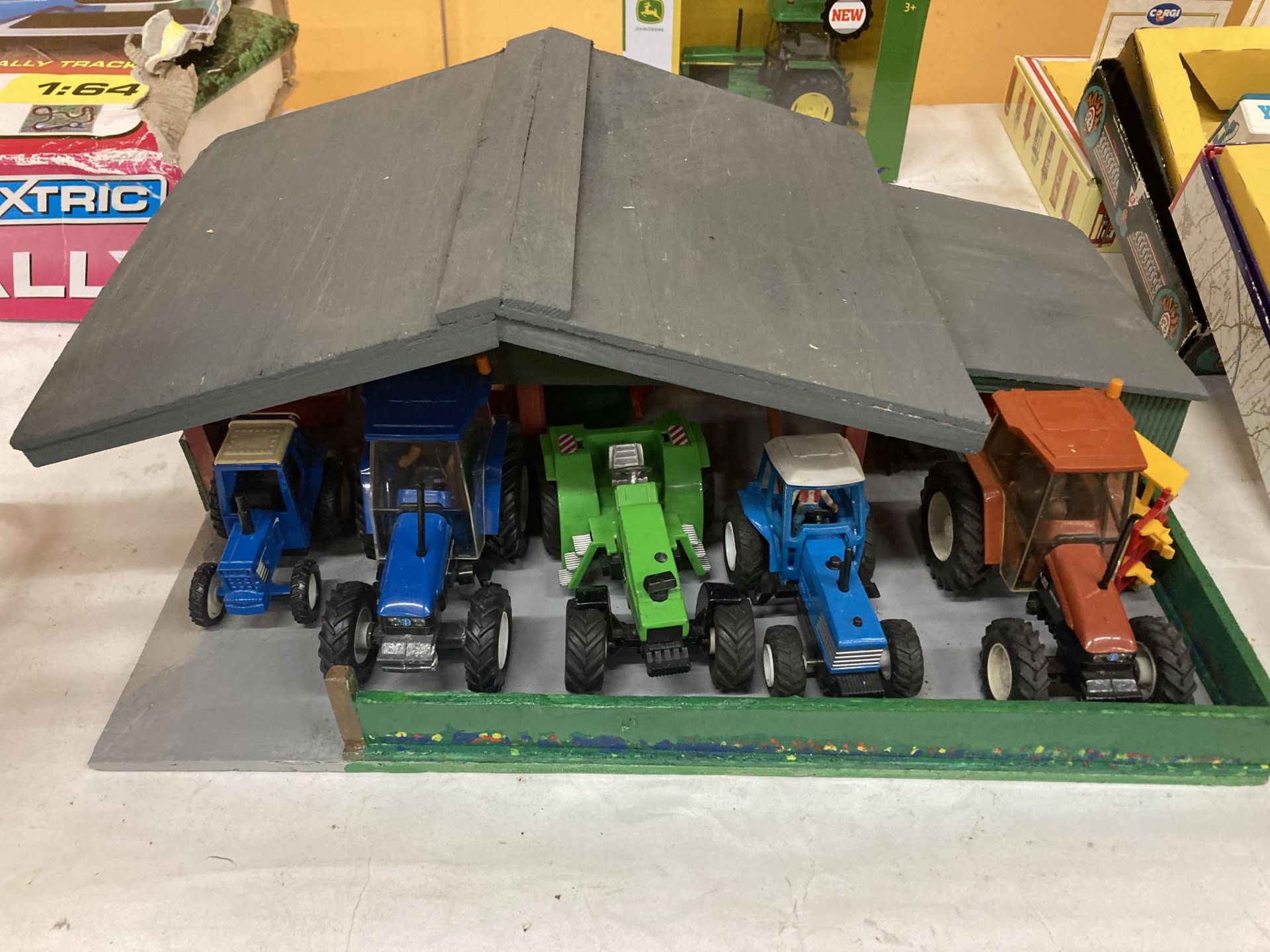 A WOODEN TRACTOR GARAGE CONTAINING A QUANTITY OF TRACTORS AND TRAILERS