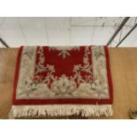 A RED AND CREAM PATTERNED FRINGED RUG