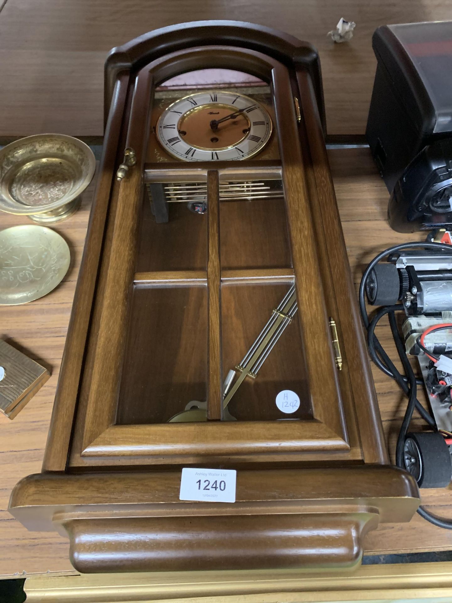 A HERMLE PENDULUM WALL CLOCK ENCASED IN MAHOGANY AND GLASS PANEL