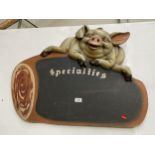 A RESTAURANT CHALK BOARD 'SPECIALITIES' DECORATED WITH SMILING PIG