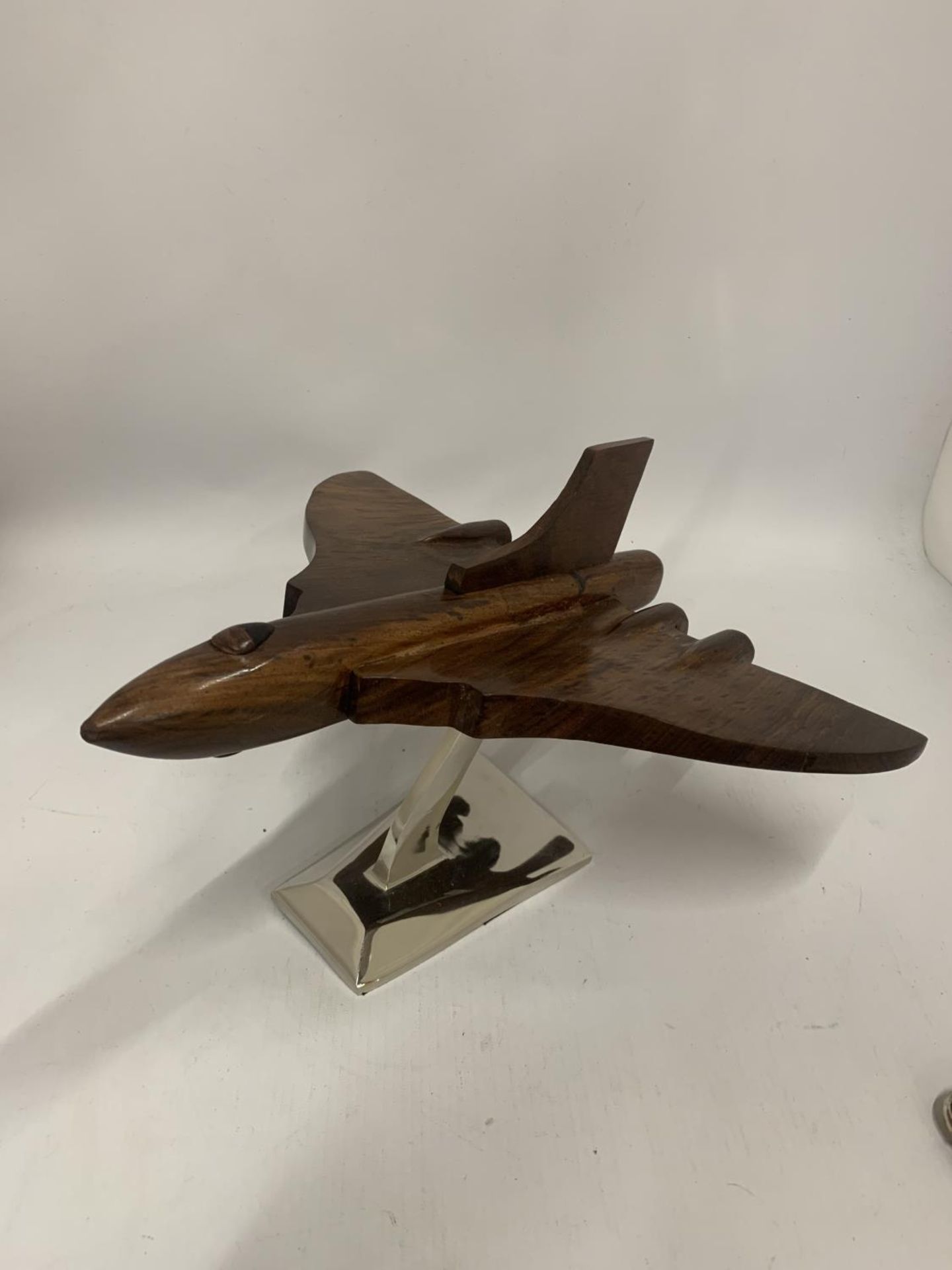 A WOODEN MODEL OF A VULCAN BOMBER ON A CHROME BASE