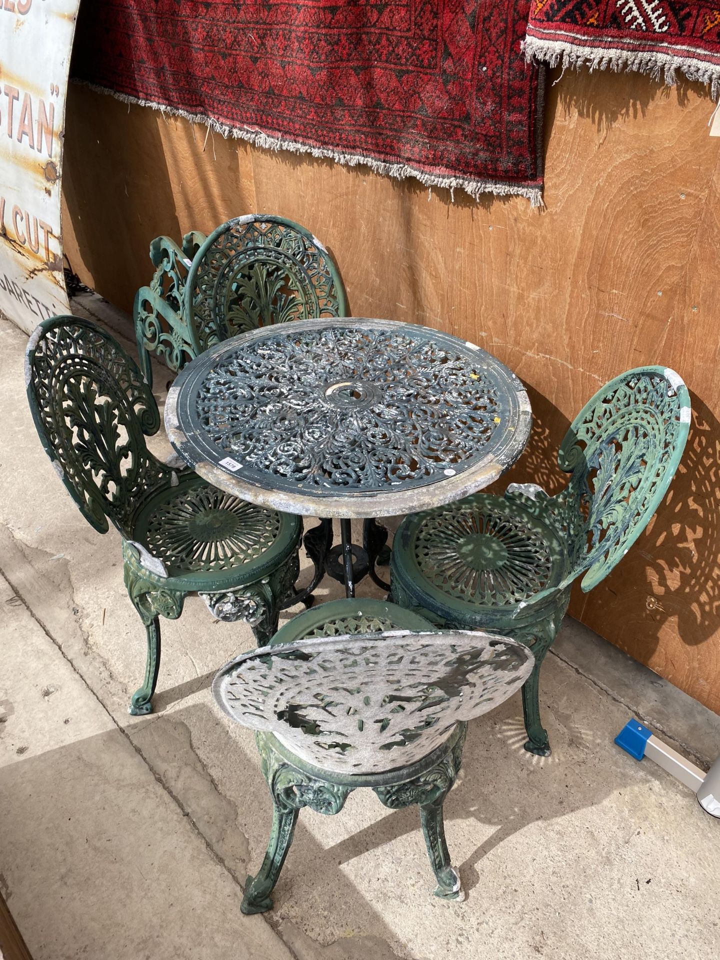 A VINTAGE CAST ALLOY BISTRO SET COMPRISING OF A ROUND TABLE AND FOUR CHAIRS