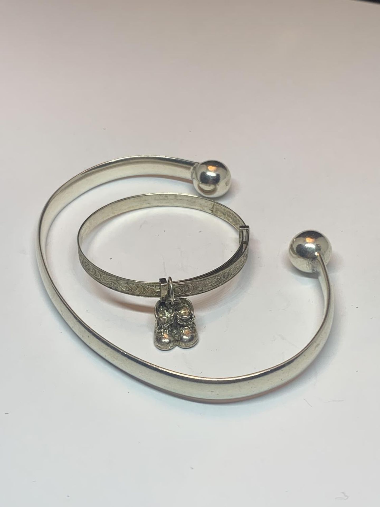 TWO SILVER BANGLES TO INCLUDE A CHILDS WITH CHARMS