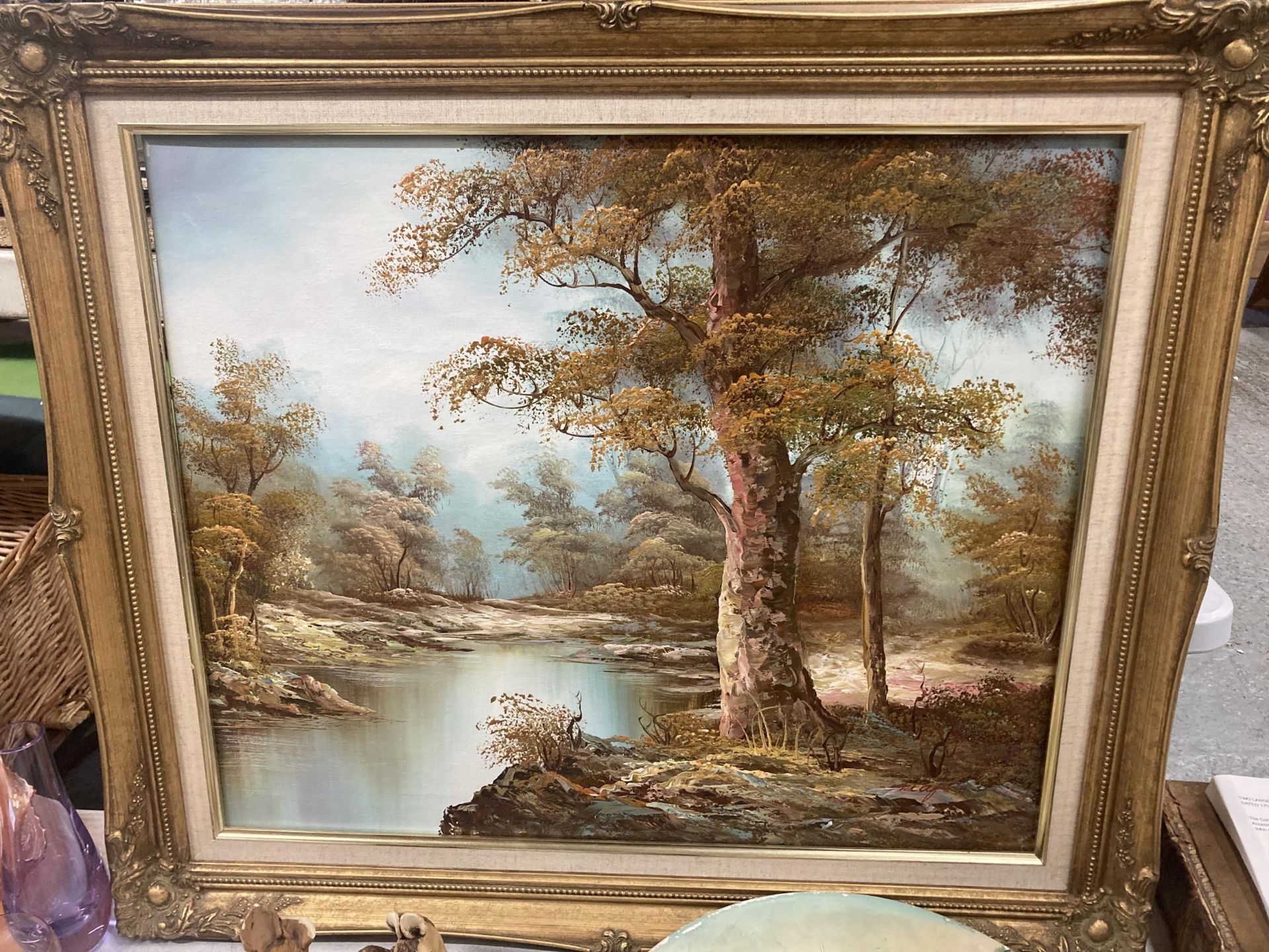 AN OIL ON CANVAS PAINTING OF A LAKE IN A WOODLAND SETTING IN A GILT FRAME 74CM X 64CM