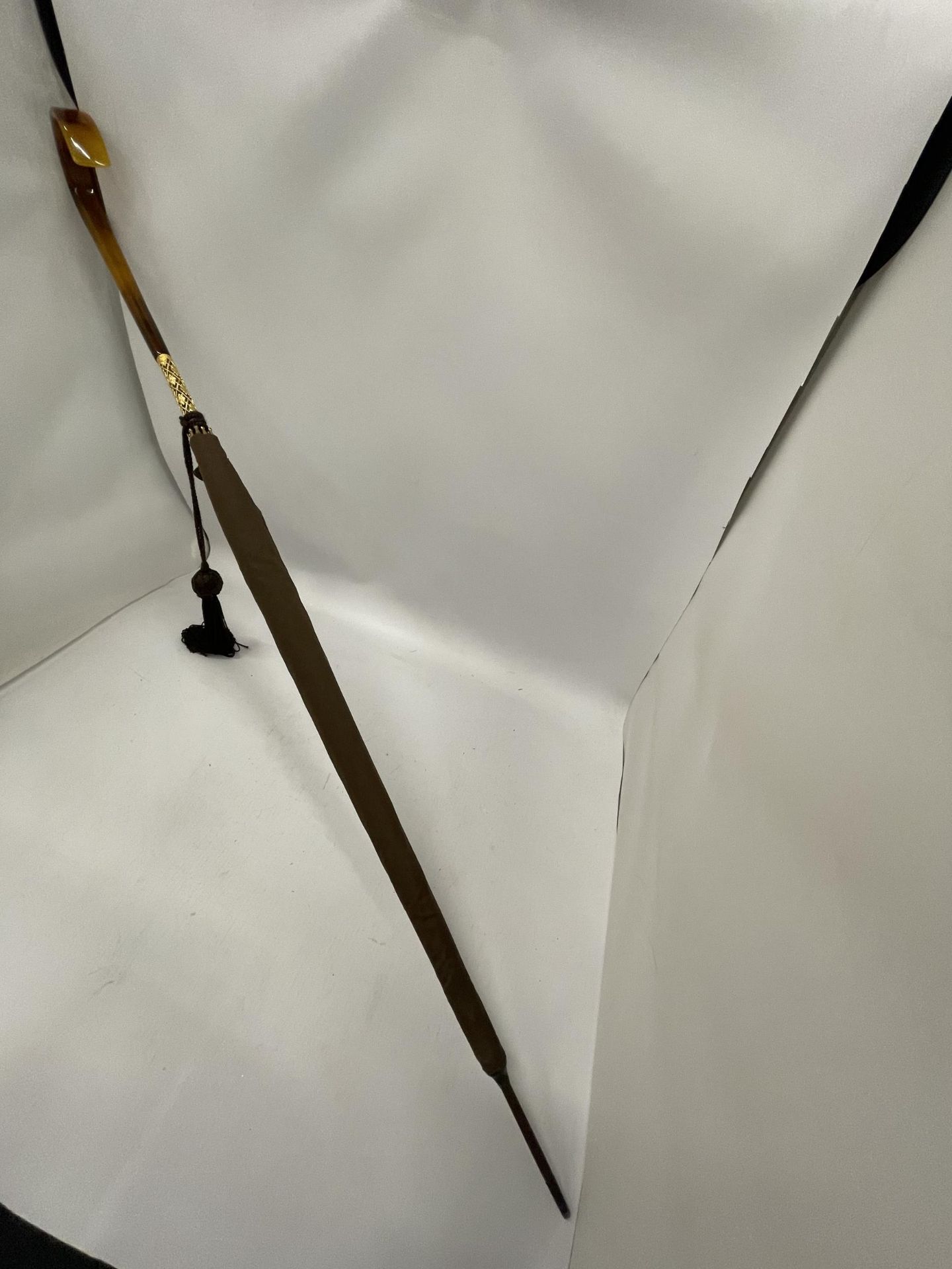 A VINTAGE PARASOL WITH DECORATIVE YELLOW METAL FERRULE AND AMBER EFFECT HANDLE