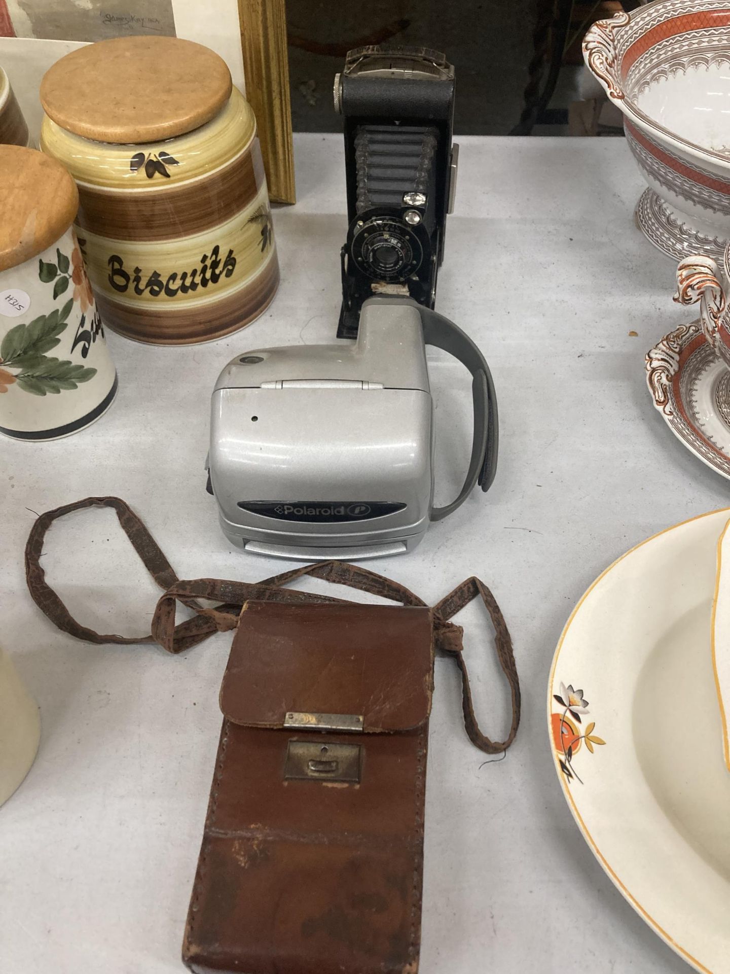 A VINTAGE KODAK CAMERA WITH BELLOWS AND LEATHER CASE AND A POLAROID CAMERA