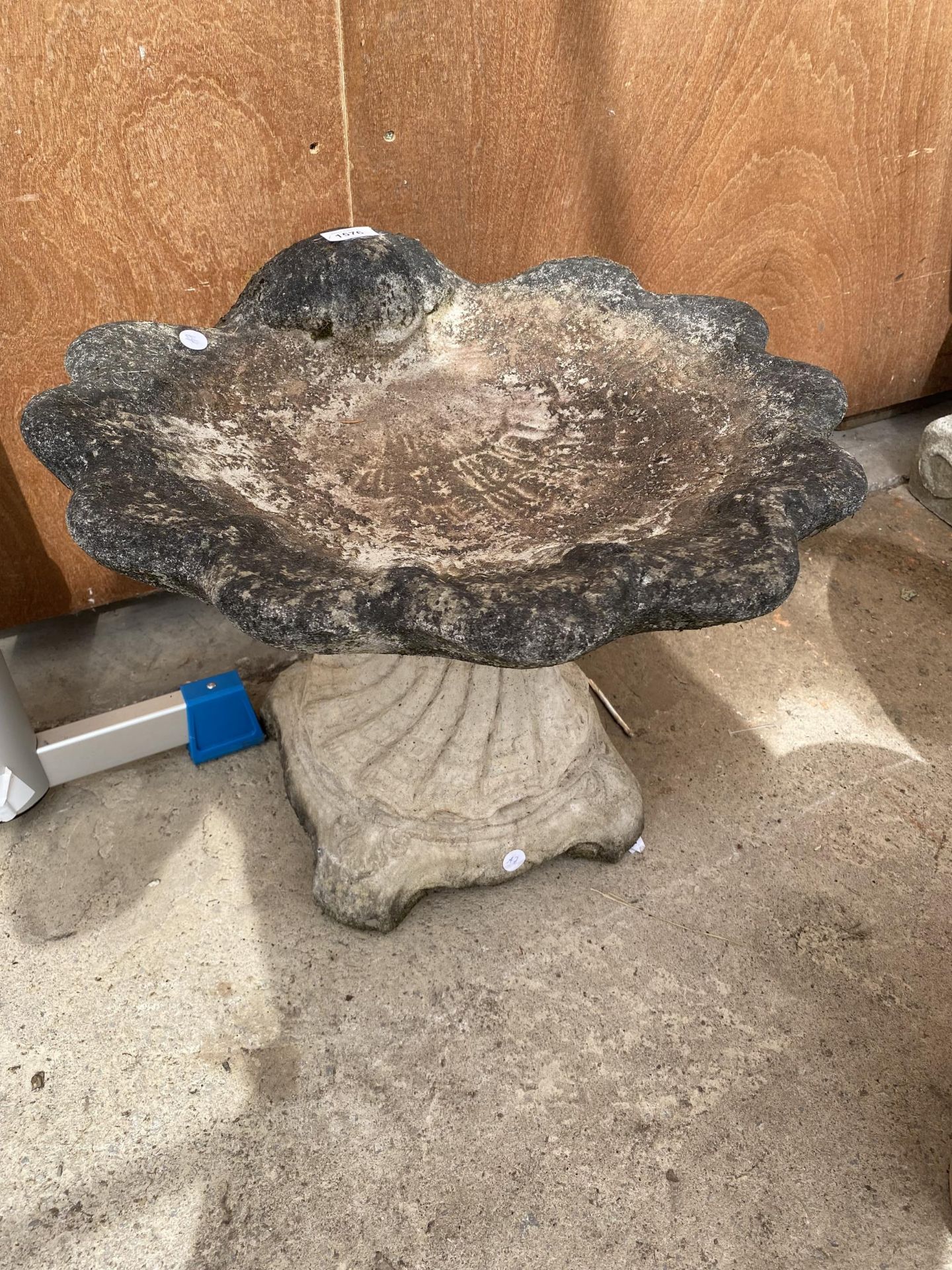 A RECONSTITUTED STONE BIRD BATH WITH PEDESTAL BASE AND SHEEL SHAPED TOP