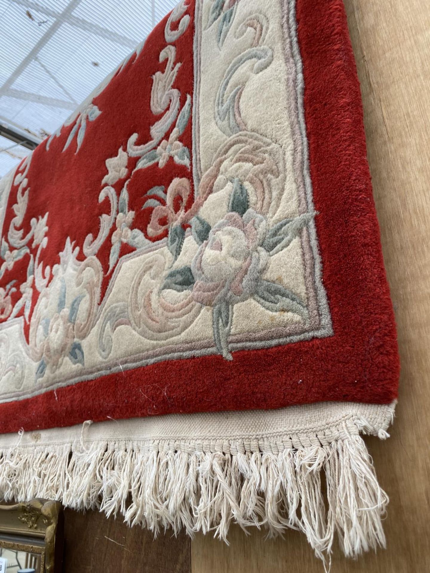 A RED AND CREAM PATTERNED FRINGED RUG - Bild 2 aus 3