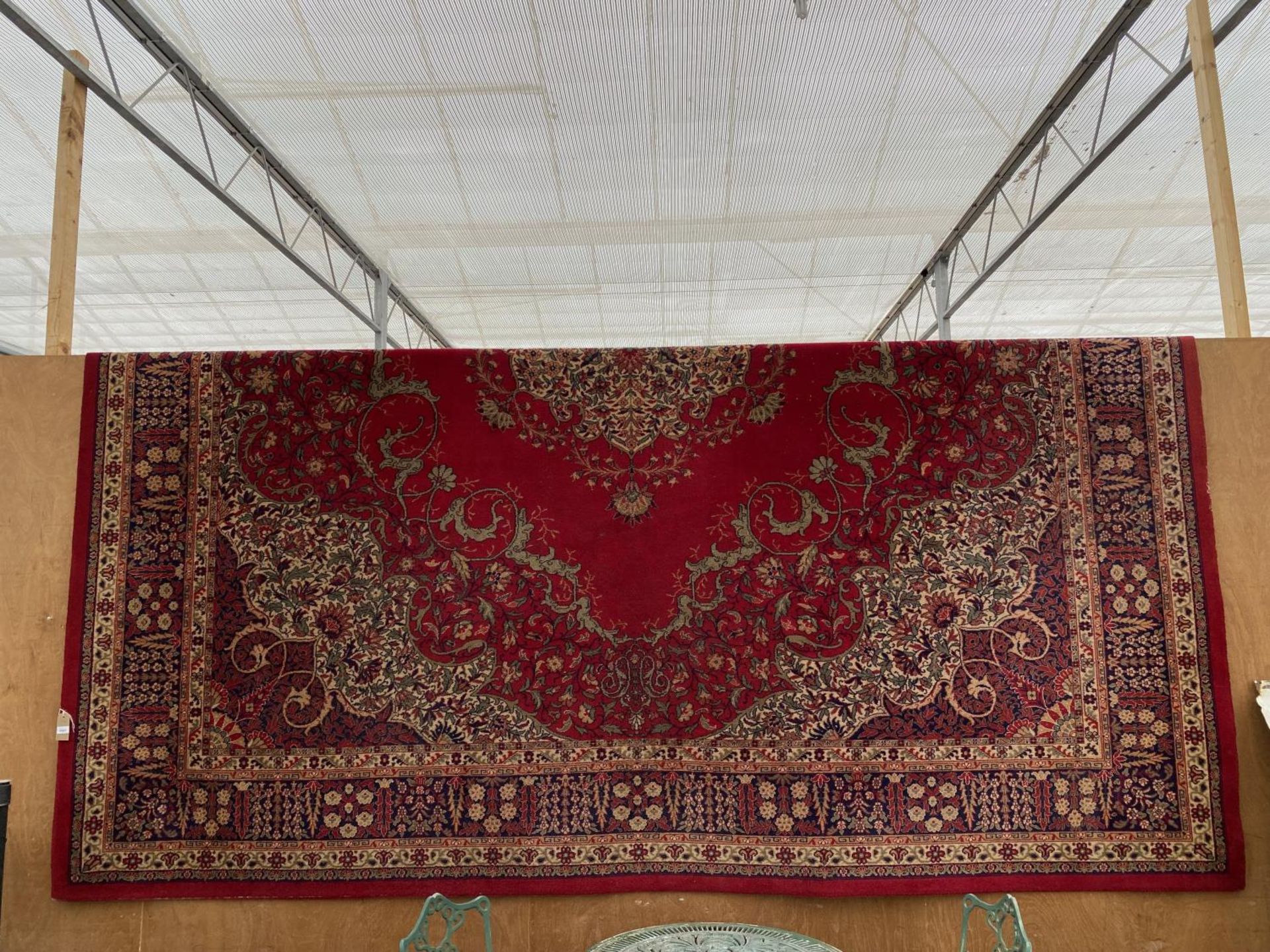 A LARGE VINTAGE RED PATTERNED RUG (3.67M X 4M APPROX)