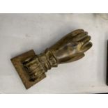 A VINTAGE BRASS DOOR KNOCKER IN THE SHAPE OF A HAND