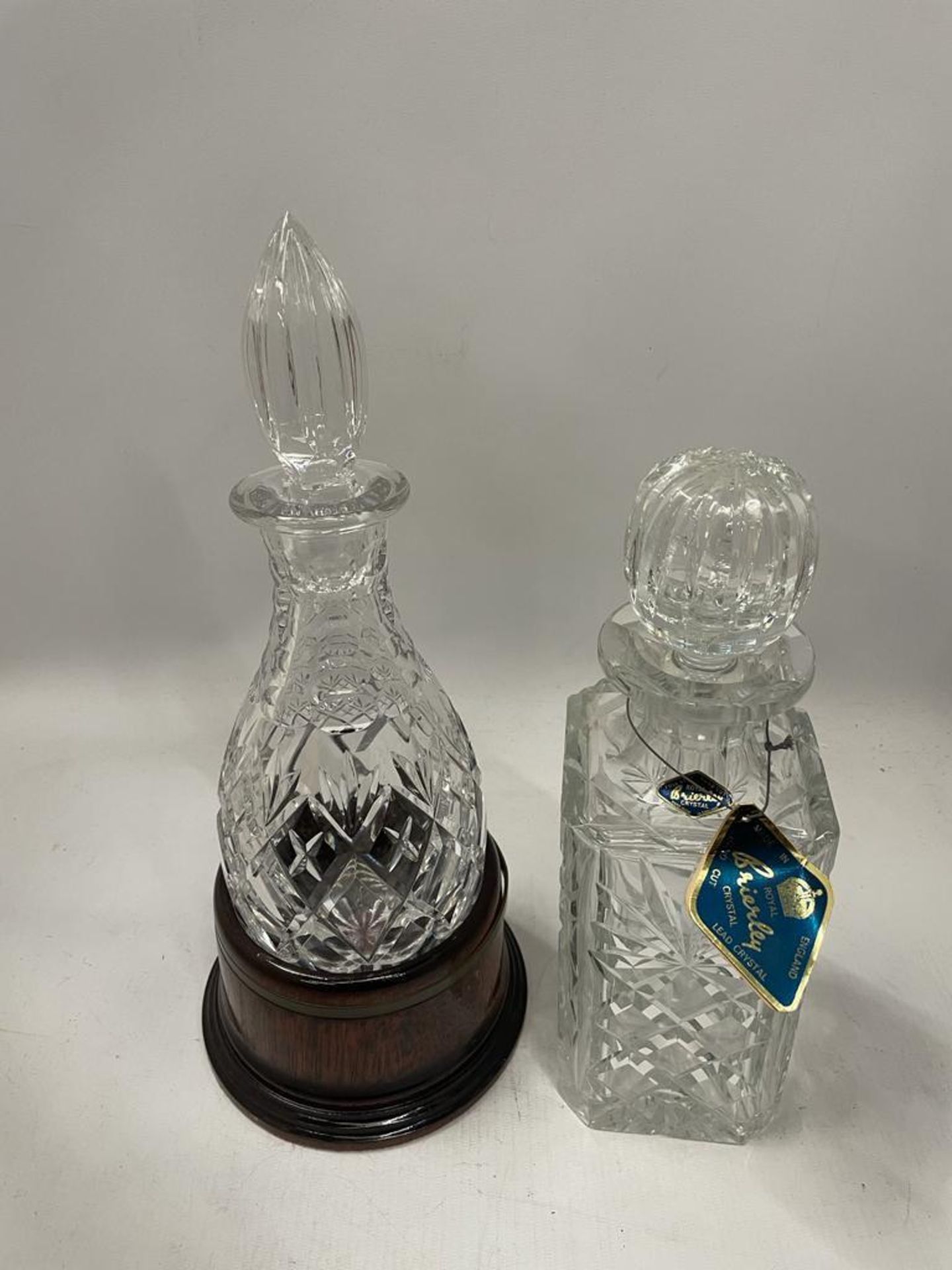 TWO CUT GLASS DECANTERS TO INCLUDE A ROYAL BRIERLEY EXAMPLE AND EXAMPLE ON WOODEN BASE