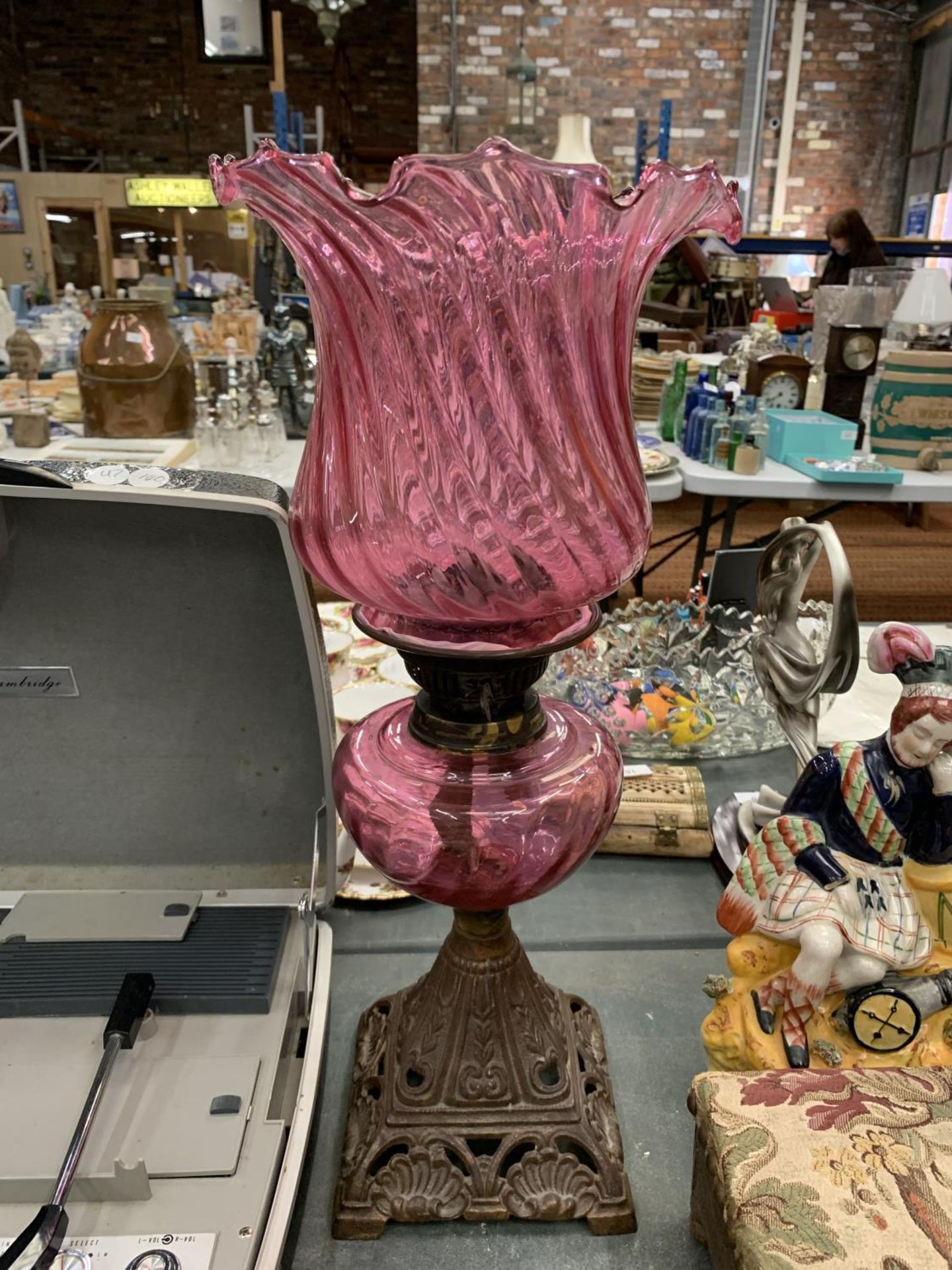 A VINTAGE OIL LAMP WITH AN ORNATE BRASS BASE AND CRANBERRY GLASS SHADE HEIGHT APPROX 47CM