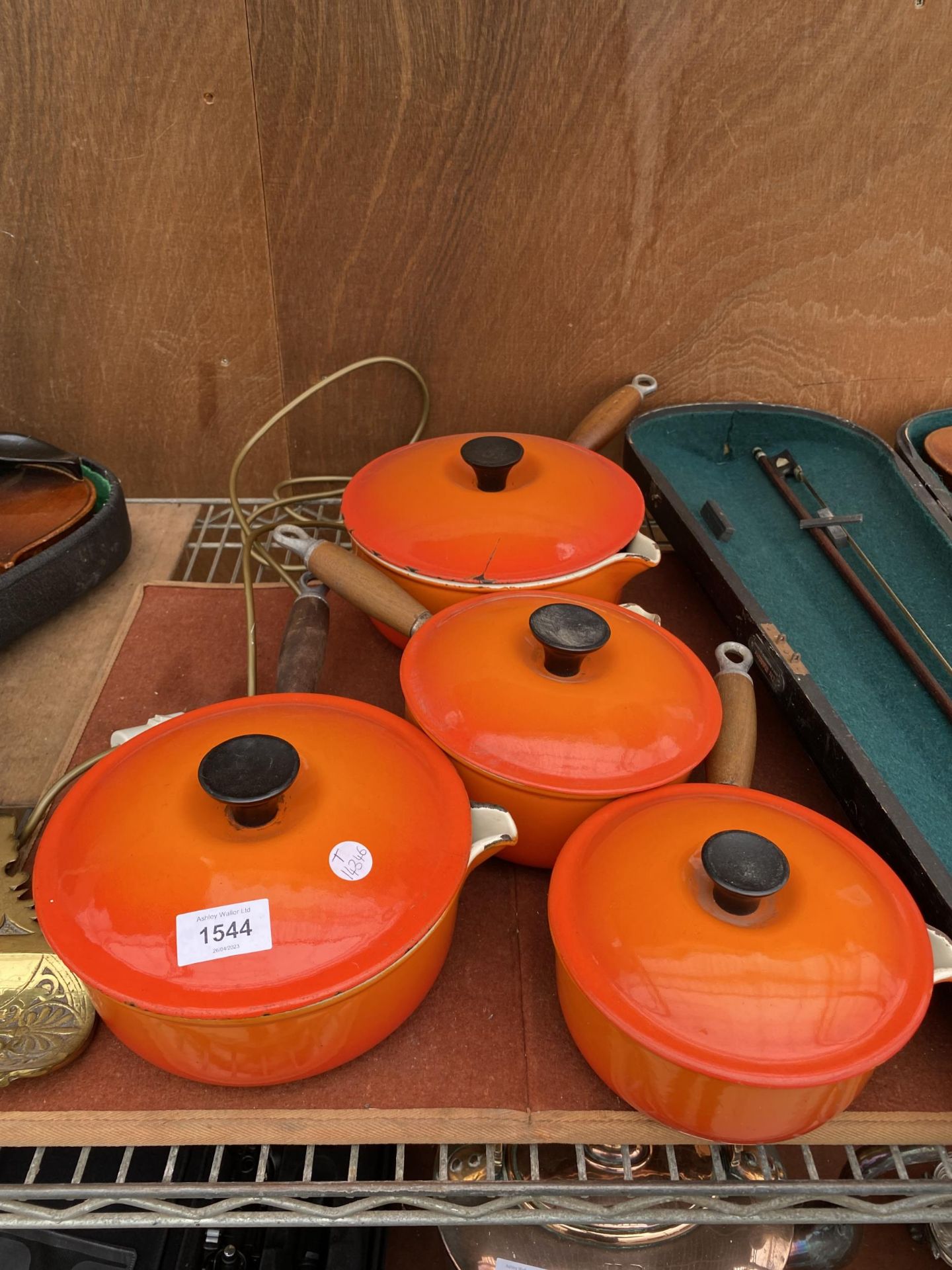 FOUR GRADUATED ORANGE LE CREUSET PANS WITH LIDS AND WOODEN HANDLES