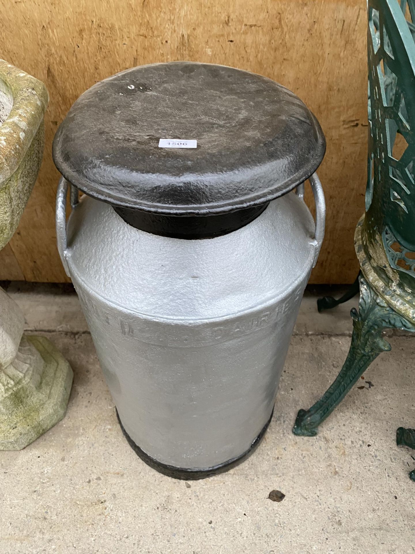 AN ALUMINIUM MILK CHURN WITH LID AND BEARING THE NAME 'UNITED DAIRIES'