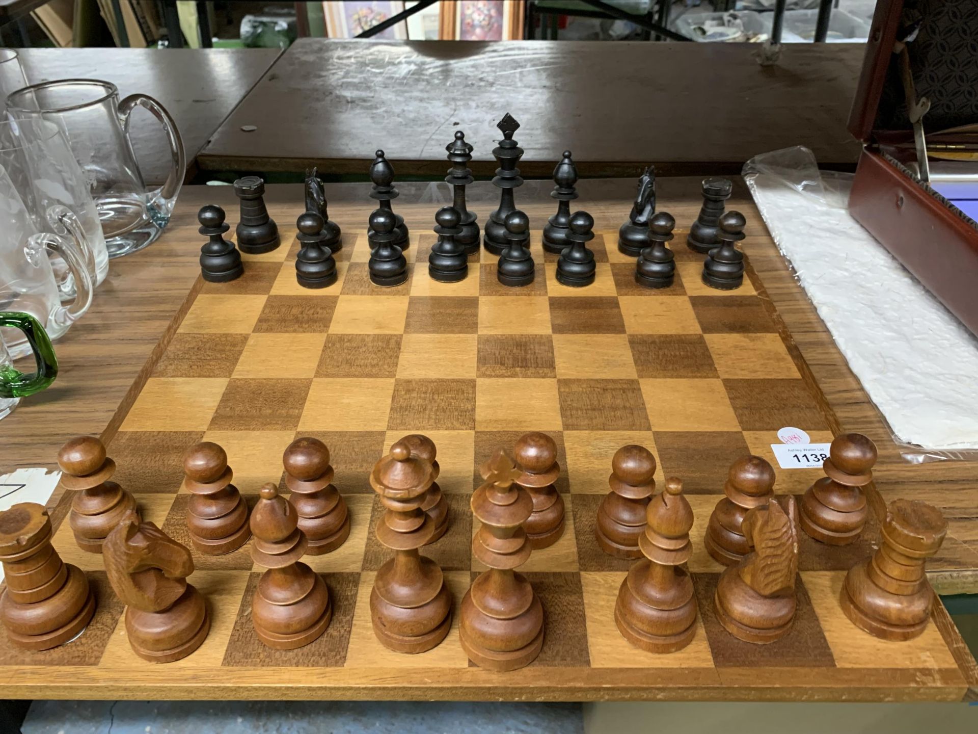 A LARGE WOODEN CHESSBOARD WITH A FULL SET OF WOODEN CHESS PIECES