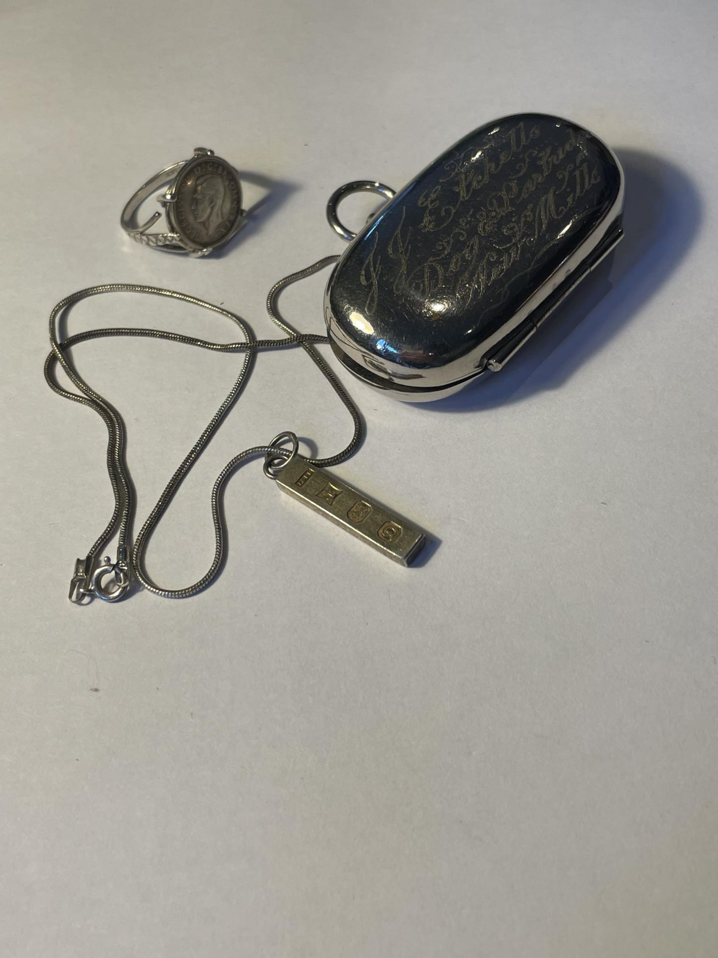 A SILVER NECKLACE WITH INGOT PENDANT, A SILVER RING WITH GEORGE V 1937 THREE PENCE AND A SILVER