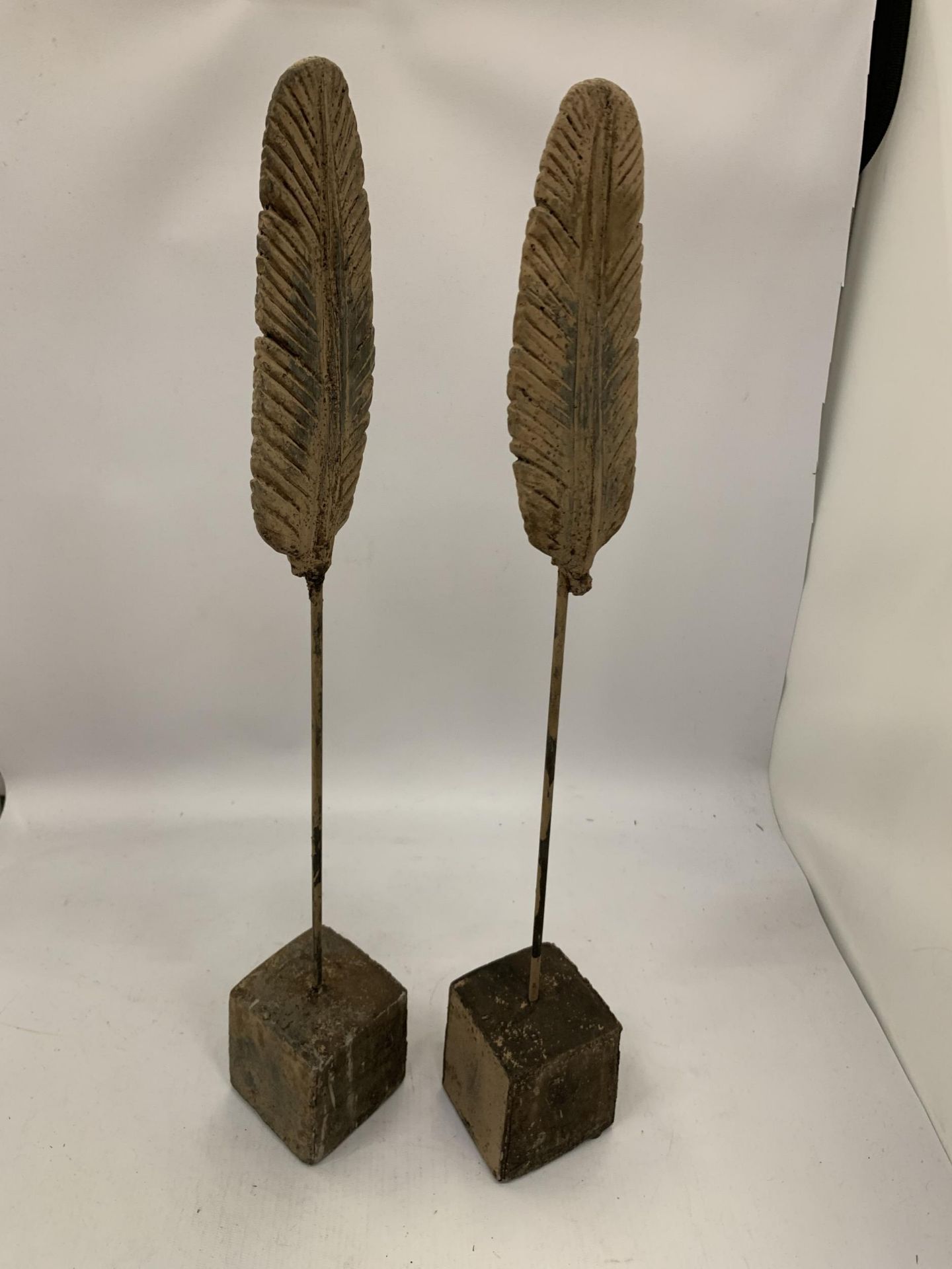 A PAIR OF DECORATIVE STONE FEATHERS ON STANDS
