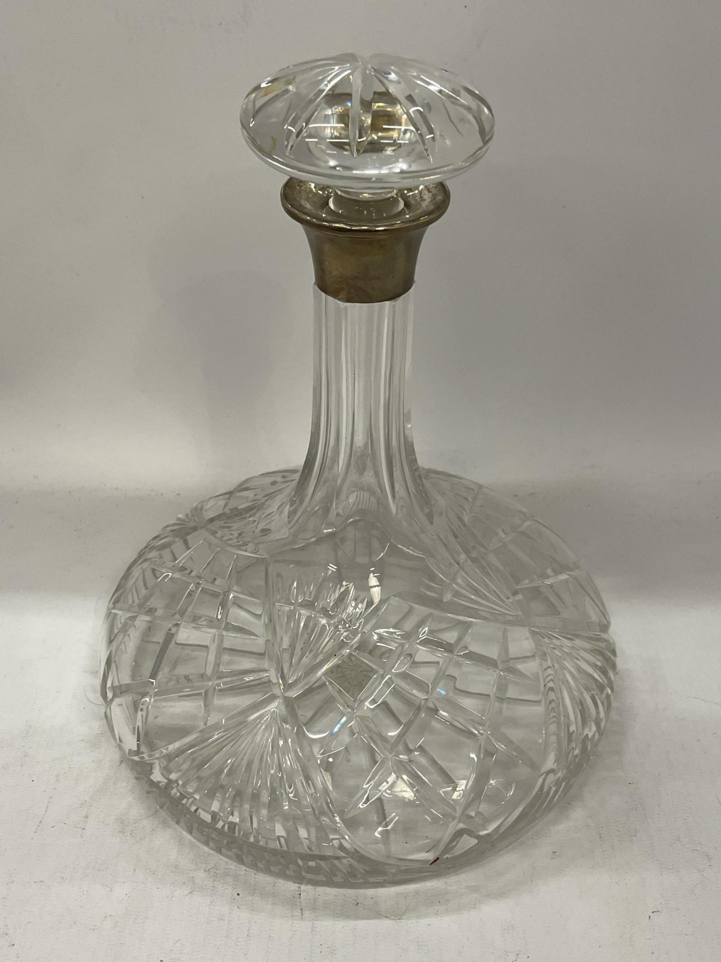 A CUT GLASS SHIPS DECANTER WITH HALLMARKED SILVER COLLAR