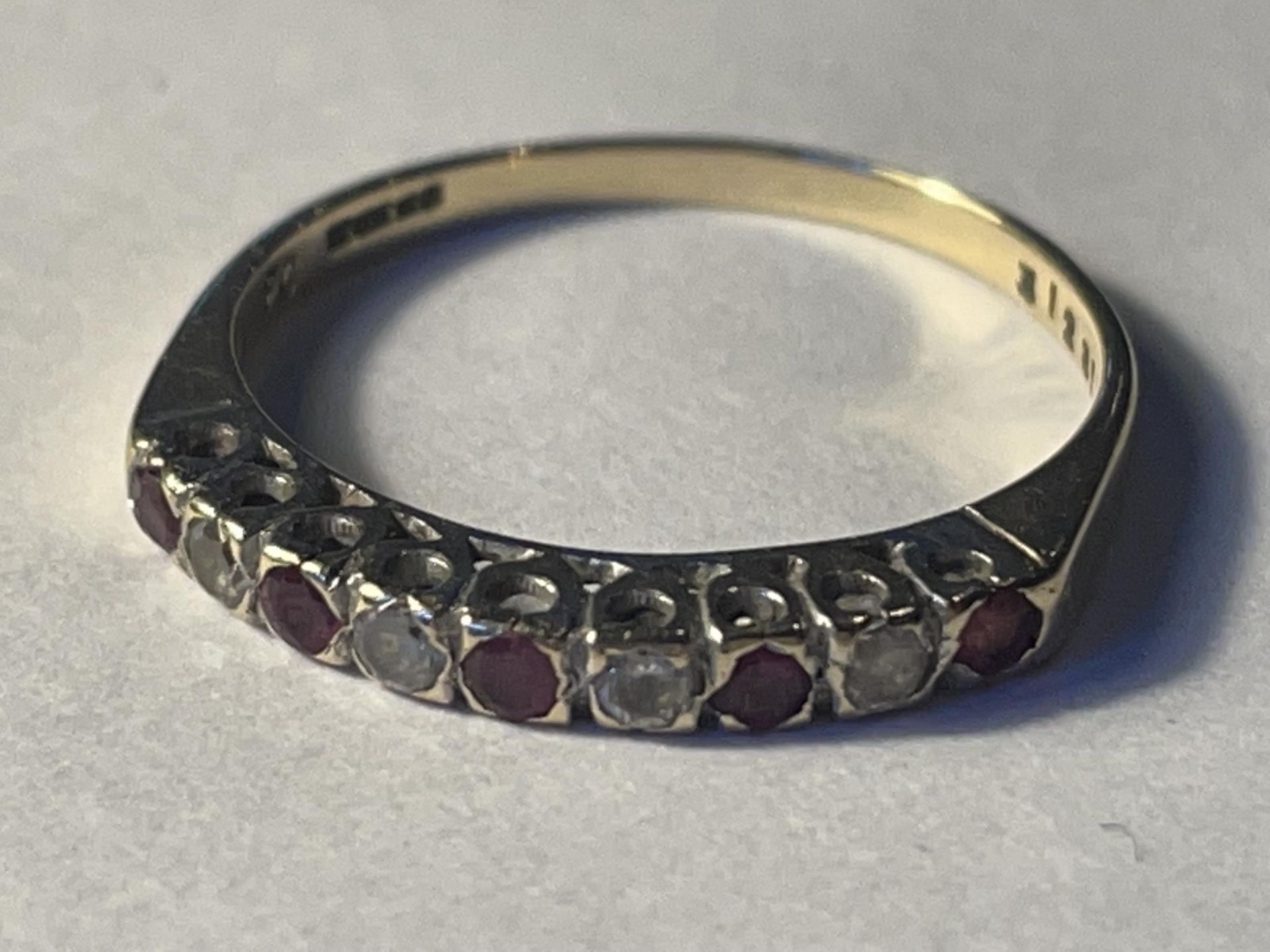 A 9 CARAT GOLD RING WITH FIVE CLEAR STONES AND FOUR REDSTONES IN A LINE GROSS WEIGHT 1.35 GRAMS SIZE