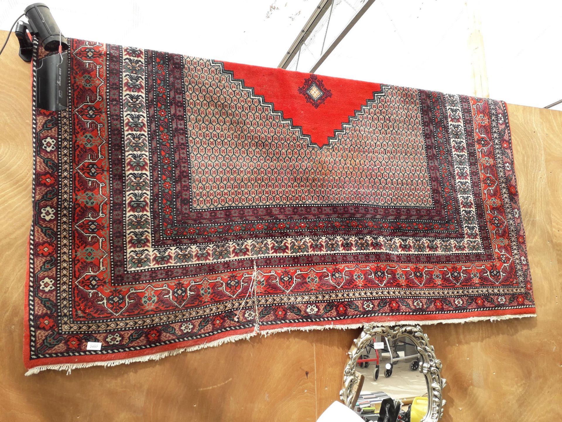 A VINTAGE RED PATTERNED FRINGED RUG