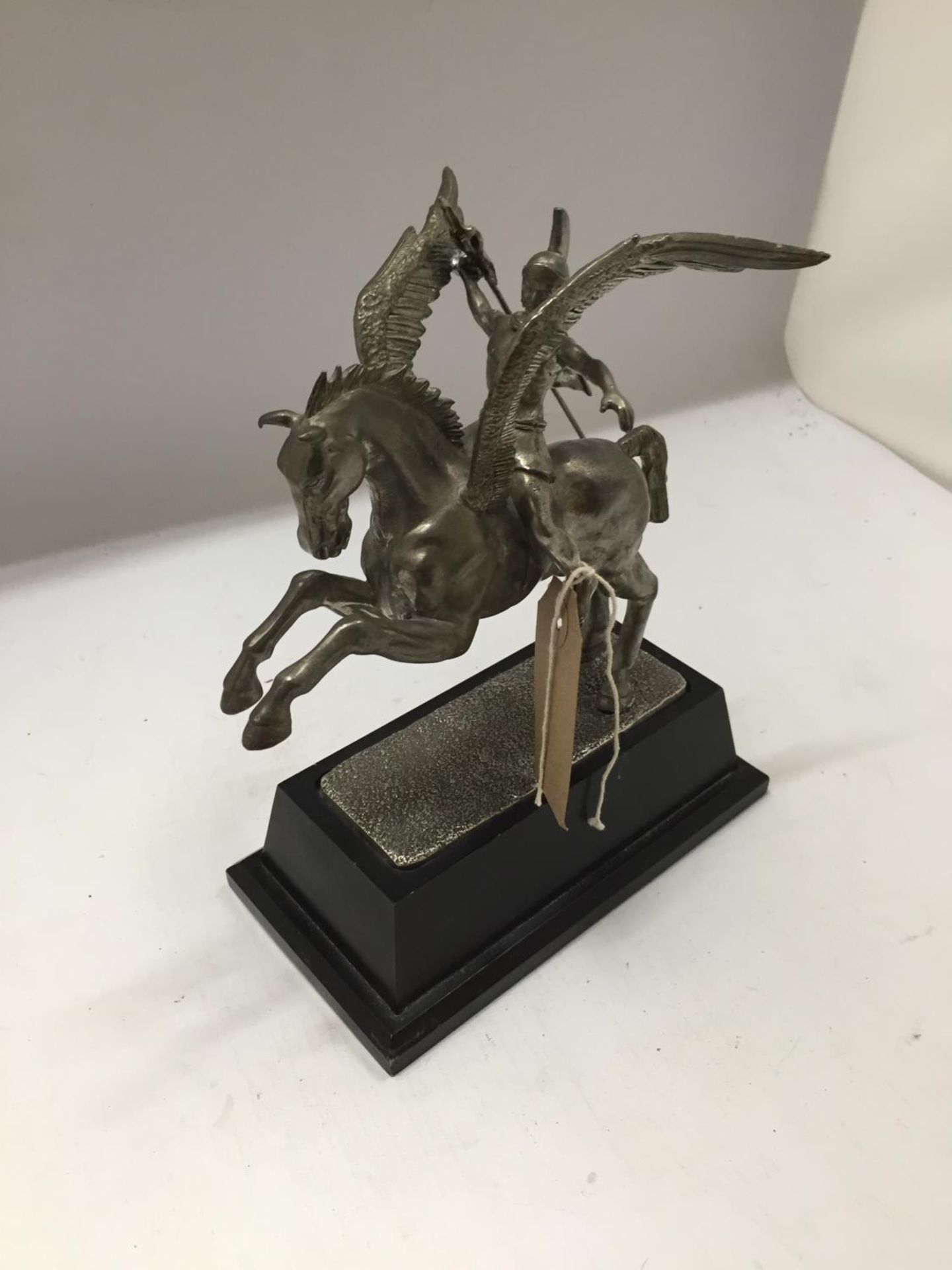A WHITE METAL MODEL OF PEGASUS BEING RIDDEN BY PERSEUS, MOUNTED ON A BLACK WOODEN BASE,HEIGHT