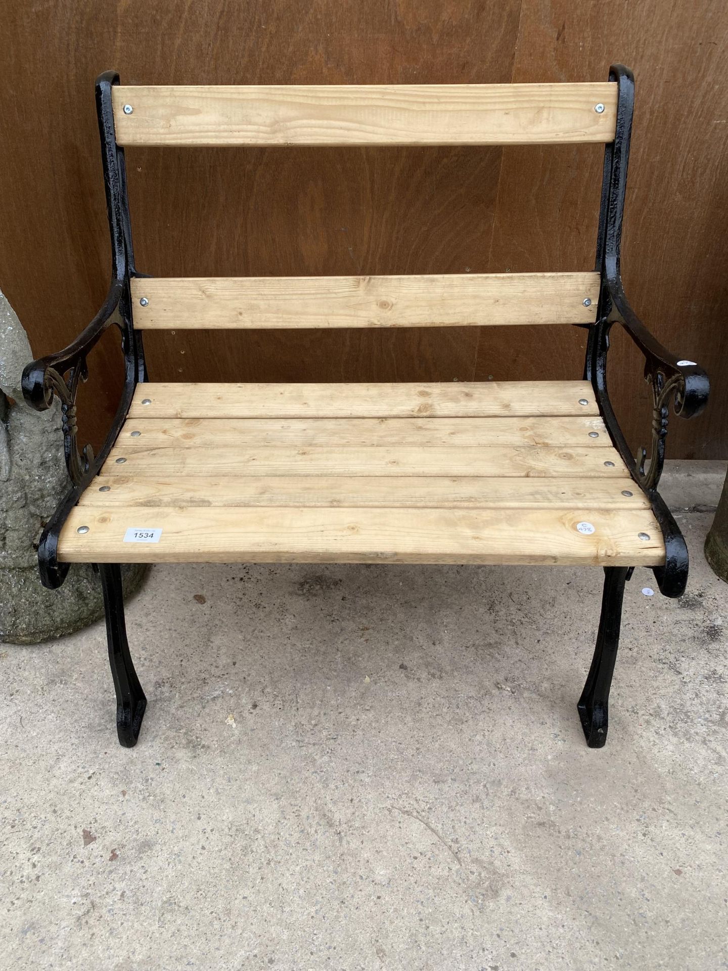 A WOODEN SLATTED WIDE GARDEN CHAIR WITH CAST IRON ENDS