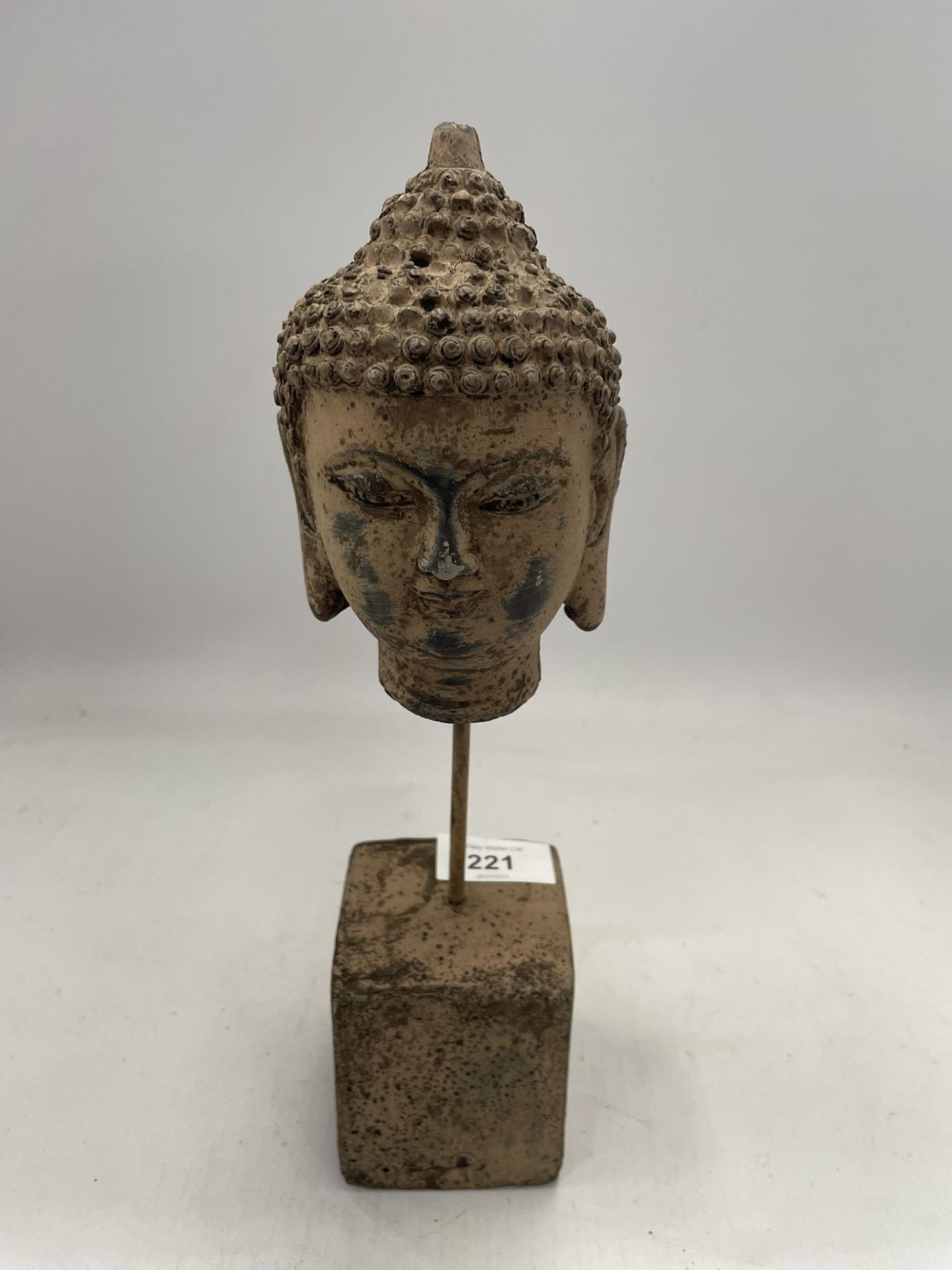 A DECORATIVE STONE BUDDAHS HEAD ON A PLINTH