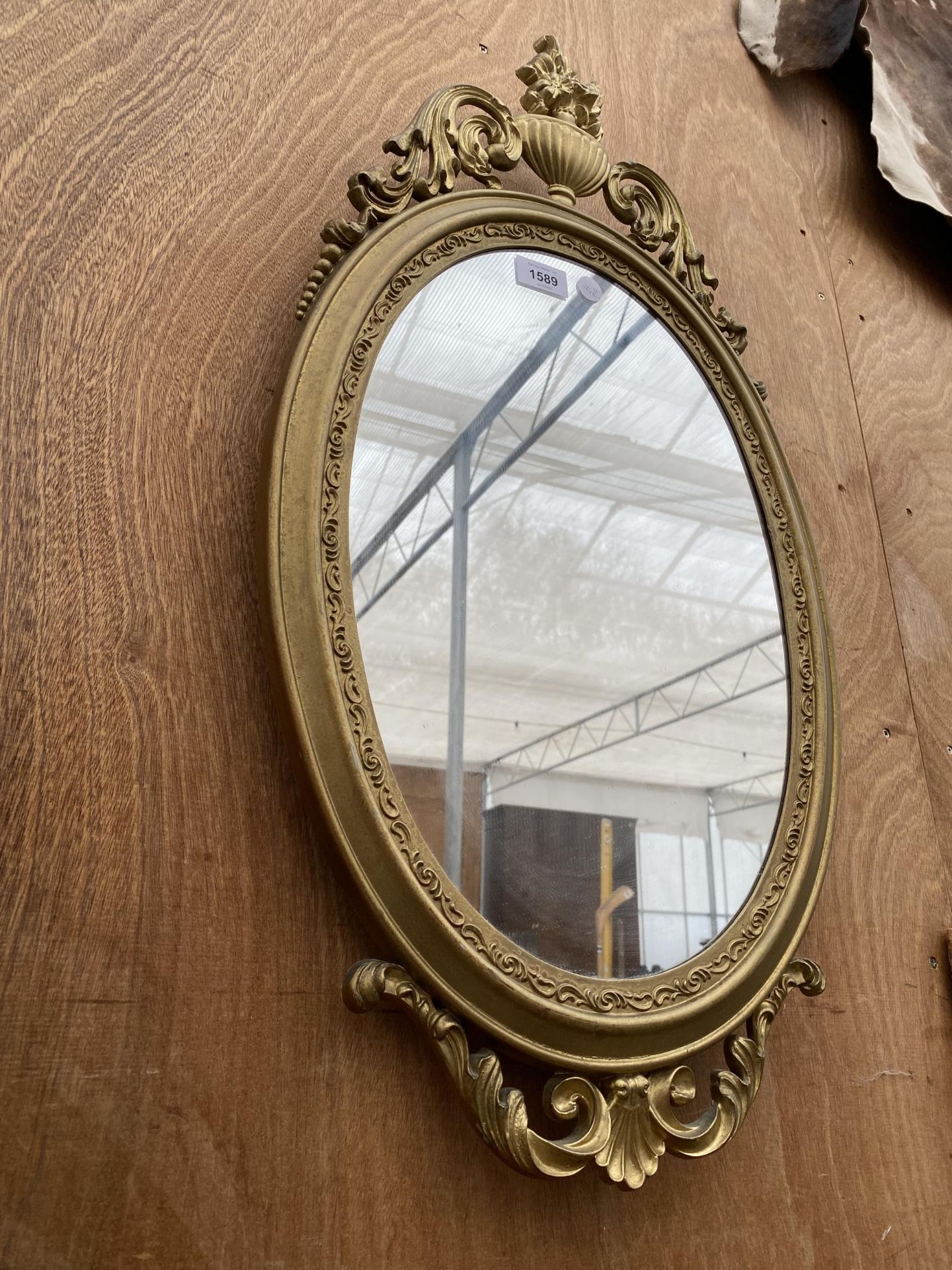 A DECORATIVE OVAL GILT FRAMED WALL MIRROR