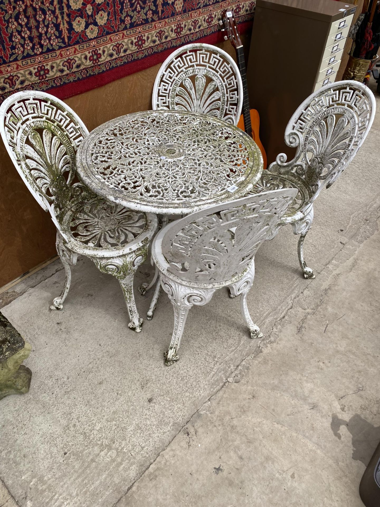 A WHITE VINTAGE CAST ALLOY BISTRO SET COMPRISING OF A ROUND TABLE AND FOUR CHAIRS