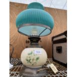 A SMALL BRASS AND CERAMIC OIL LAMP CONVERTED TO ELECTRIC AND COMPLETE WITH GREEN GLASS SHADE