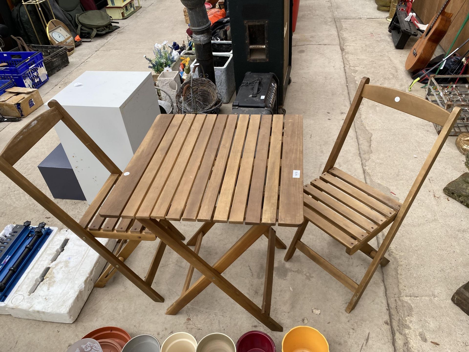 A TEAK FOLDING BISTRO TABLE AND TWO CHAIRS