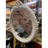 A MODERN OVAL WALL MIRROR WITH WHITE FLORAL SURROUND 56CM X 70CM