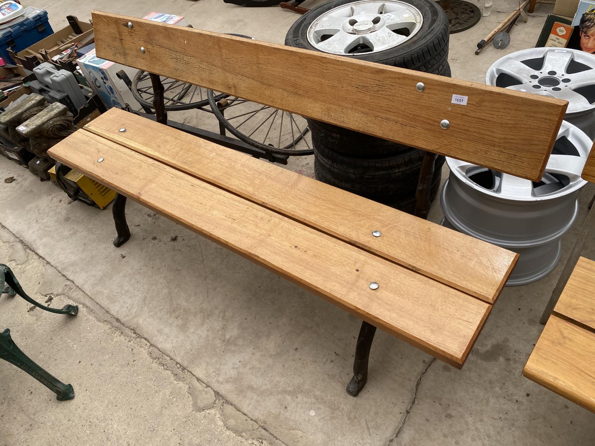 A LARGE REFURBISHED WOODEN SLATTED BENCH WITH 'KNOTTY' CAST IRON BENCH ENDS