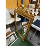 AN ORNATE GILT FRAMED MIRROR WITH RIBBON DESIGN TOP